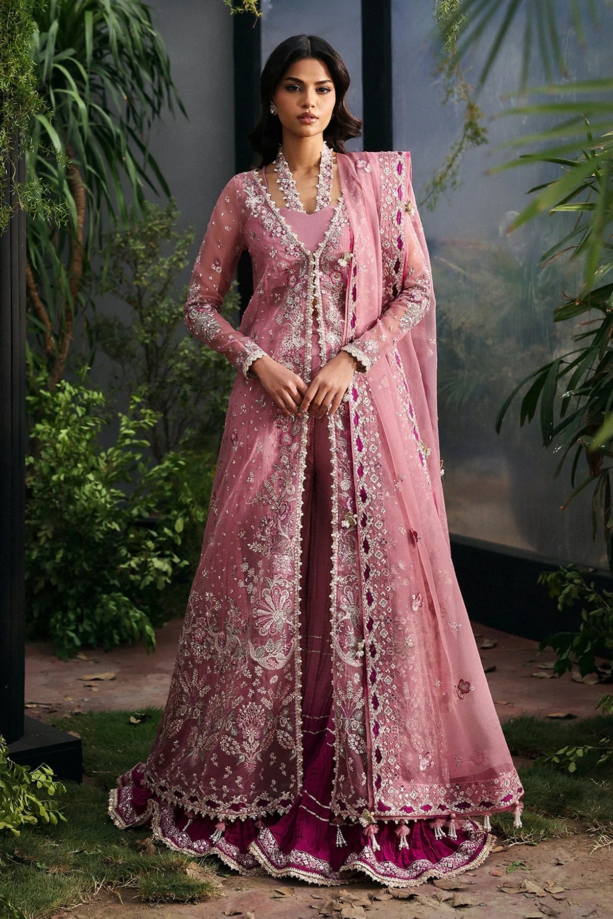 Chic pink organza dress with multi-panel embroidery, magenta silk trouser borders, and tie-dye trousers. Includes dupatta with pallu border for a vibrant look.