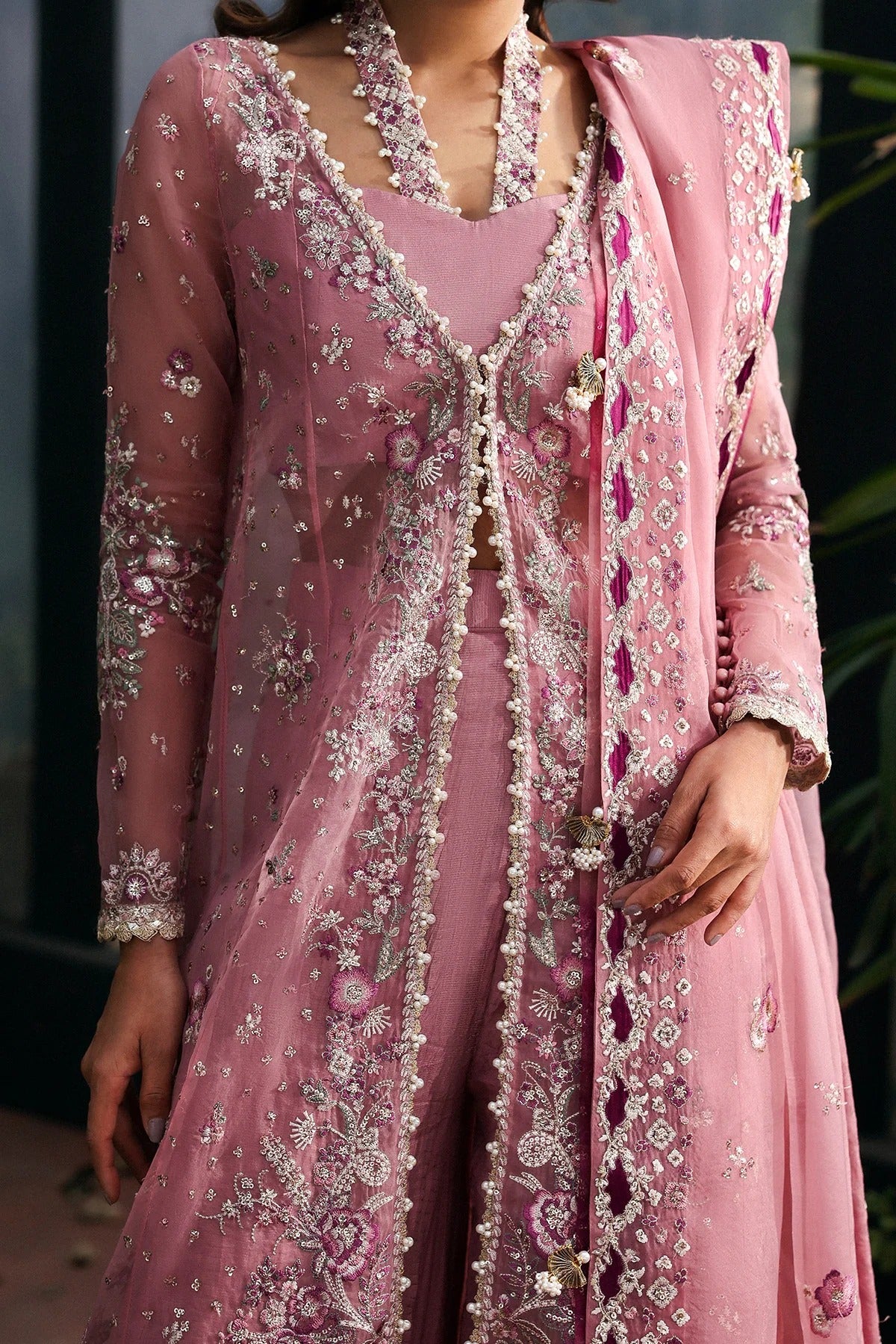 Chic pink organza dress with multi-panel embroidery, magenta silk trouser borders, and tie-dye trousers. Includes dupatta with pallu border for a vibrant look.