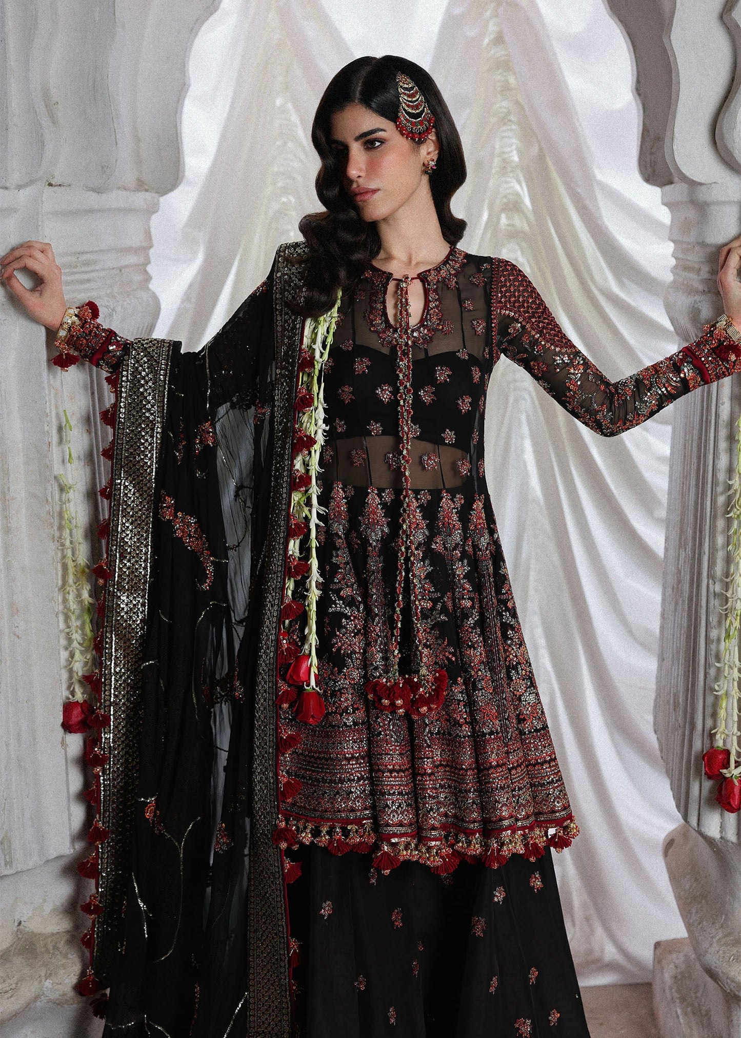 Elegant black embroidered peplum paired with flared Korean raw silk sharara and chiffon dupatta featuring delicate embroidery and four-sided borders for festive events.