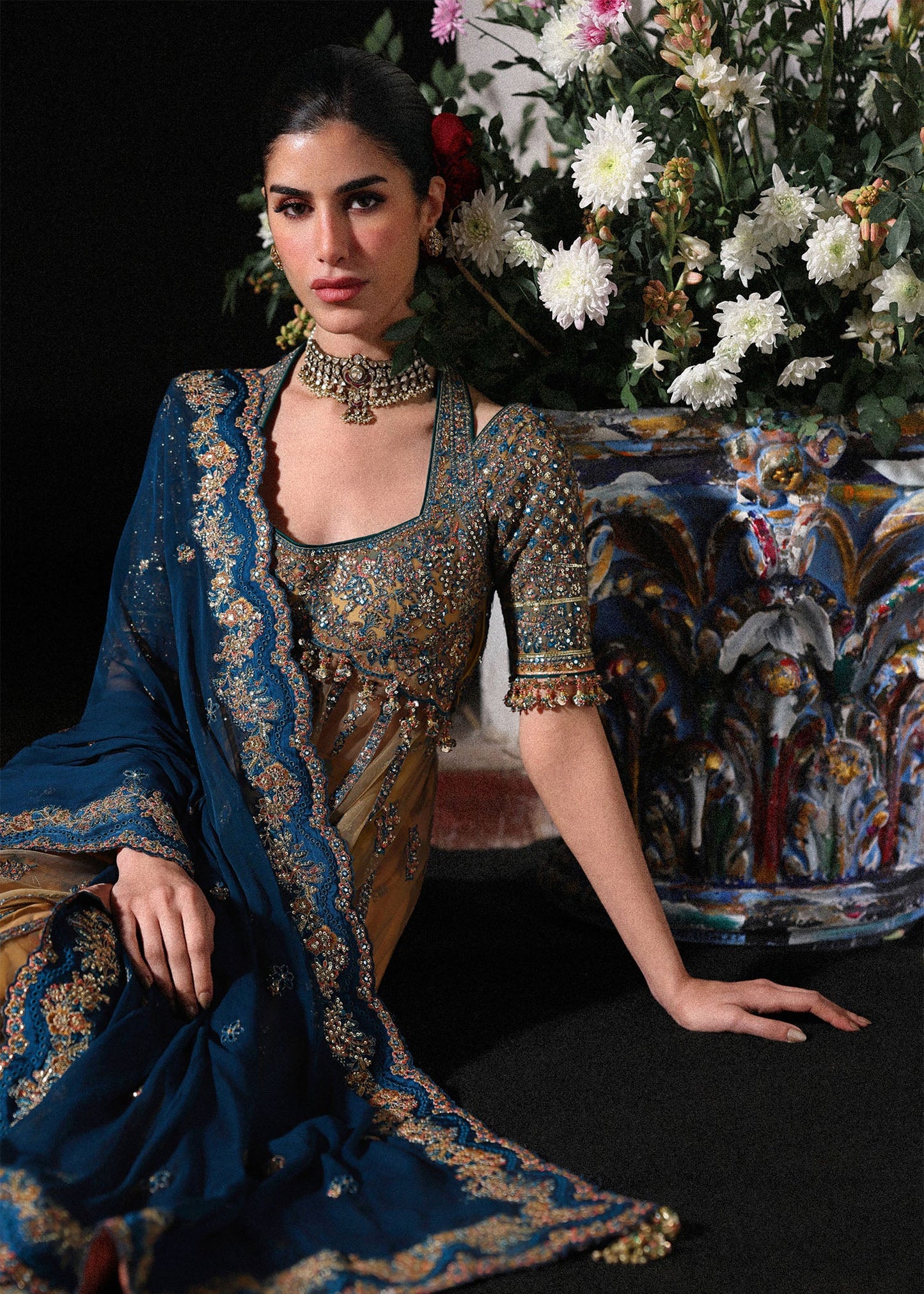 Graceful butter yellow net pishwas with embroidered panels and sleeves, paired with printed Korean raw silk sharara and a chiffon dupatta with borders.