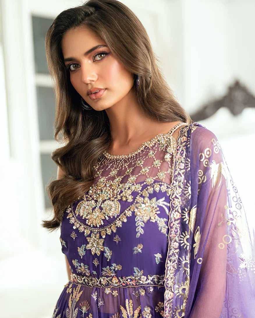 Graceful purple chiffon suit with hand embellishments, 3D daman lace, foil printed dupatta & raw silk trousers. Finished with tassels, pearls & tila lace.