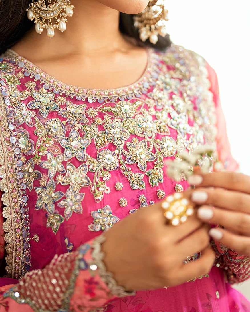 Shop this shocking pink chiffon suit with silk sleeves, lurex dupatta & raw silk trouser. Hand embellishments, sequins & tassels add a luxe festive finish!