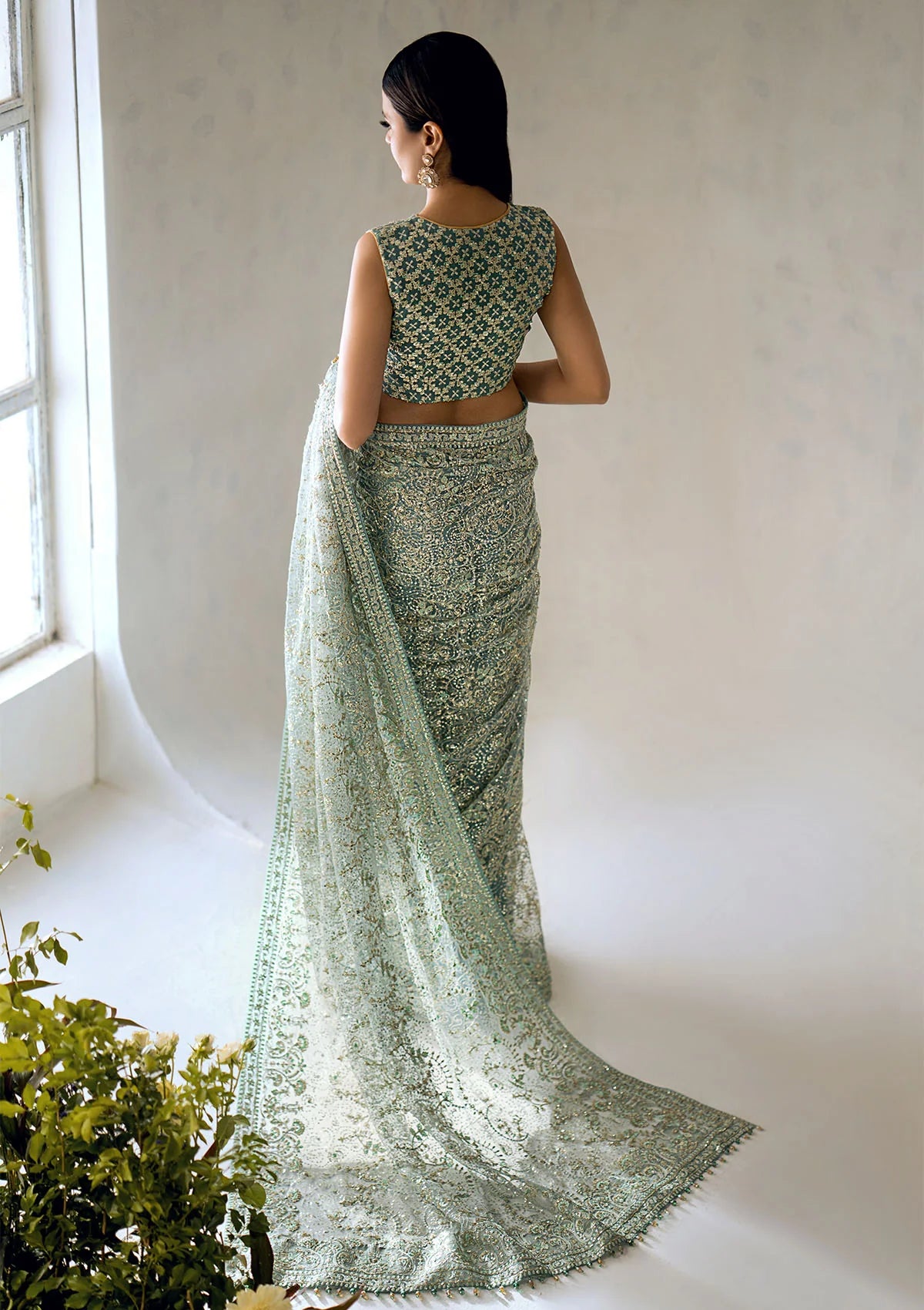 Stunning aqua tulle saree with embroidered fall and pallu, paired with a medium silk blouse featuring gold and aqua embroidery, sequins, and organza borders for festive elegance.