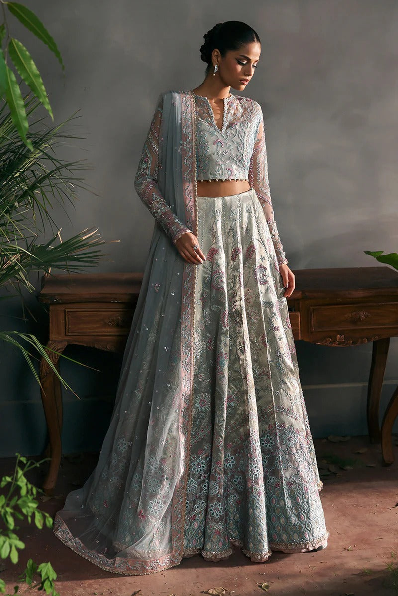Elegant aqua net suit with embroidered panels, rose pink zari borders, and raw silk trouser for a refined festive and formal look.