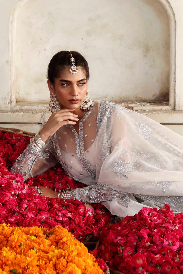 An elegant organza ensemble featuring hand-embellished panels, neckline, and sleeves. Paired with an embroidered dupatta and raw silk lehenga for a regal look.