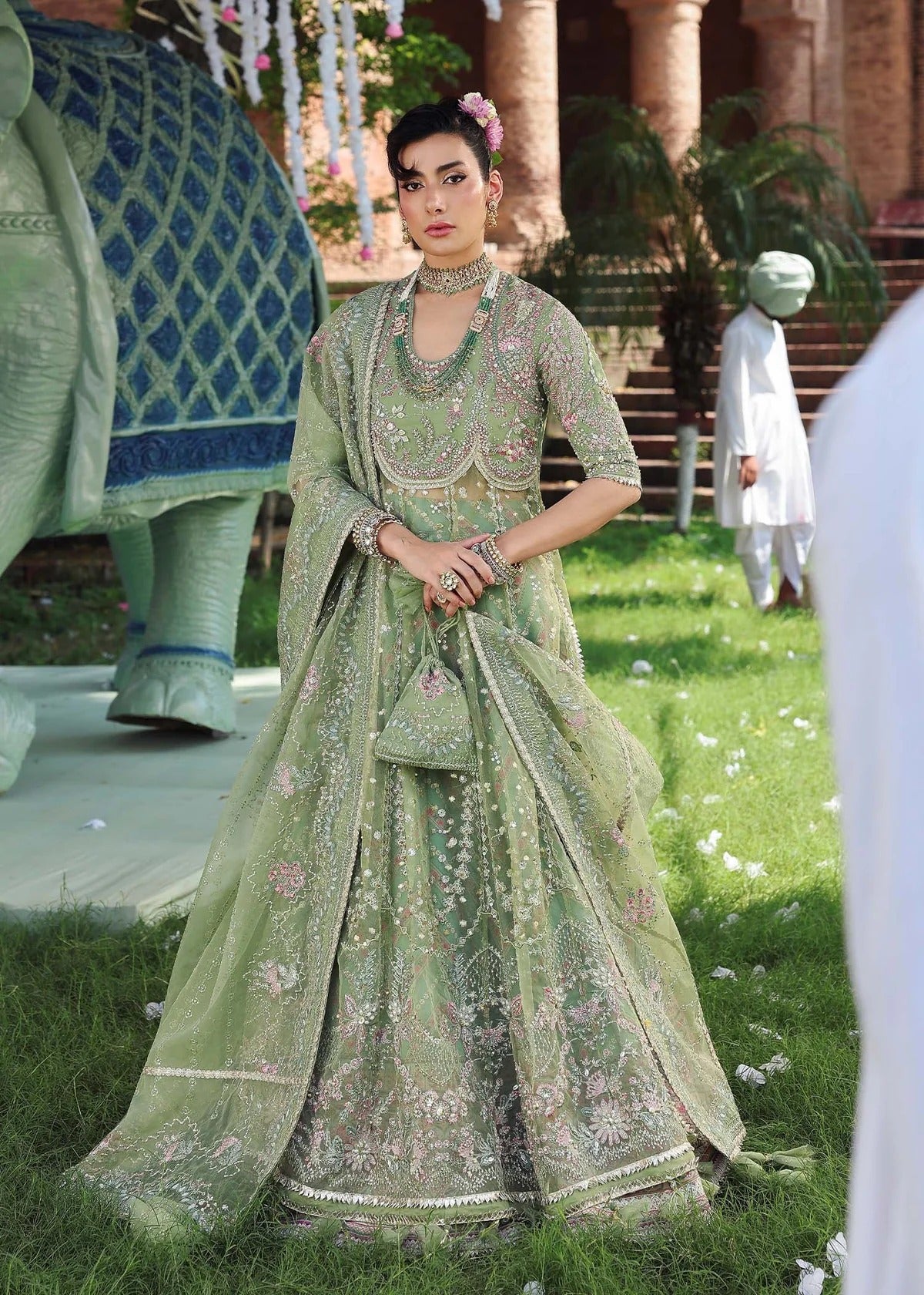 Elevate your festive look with this sage green zari organza outfit featuring delicate hand embroidery, printed raw silk trousers, and an elegant dupatta.