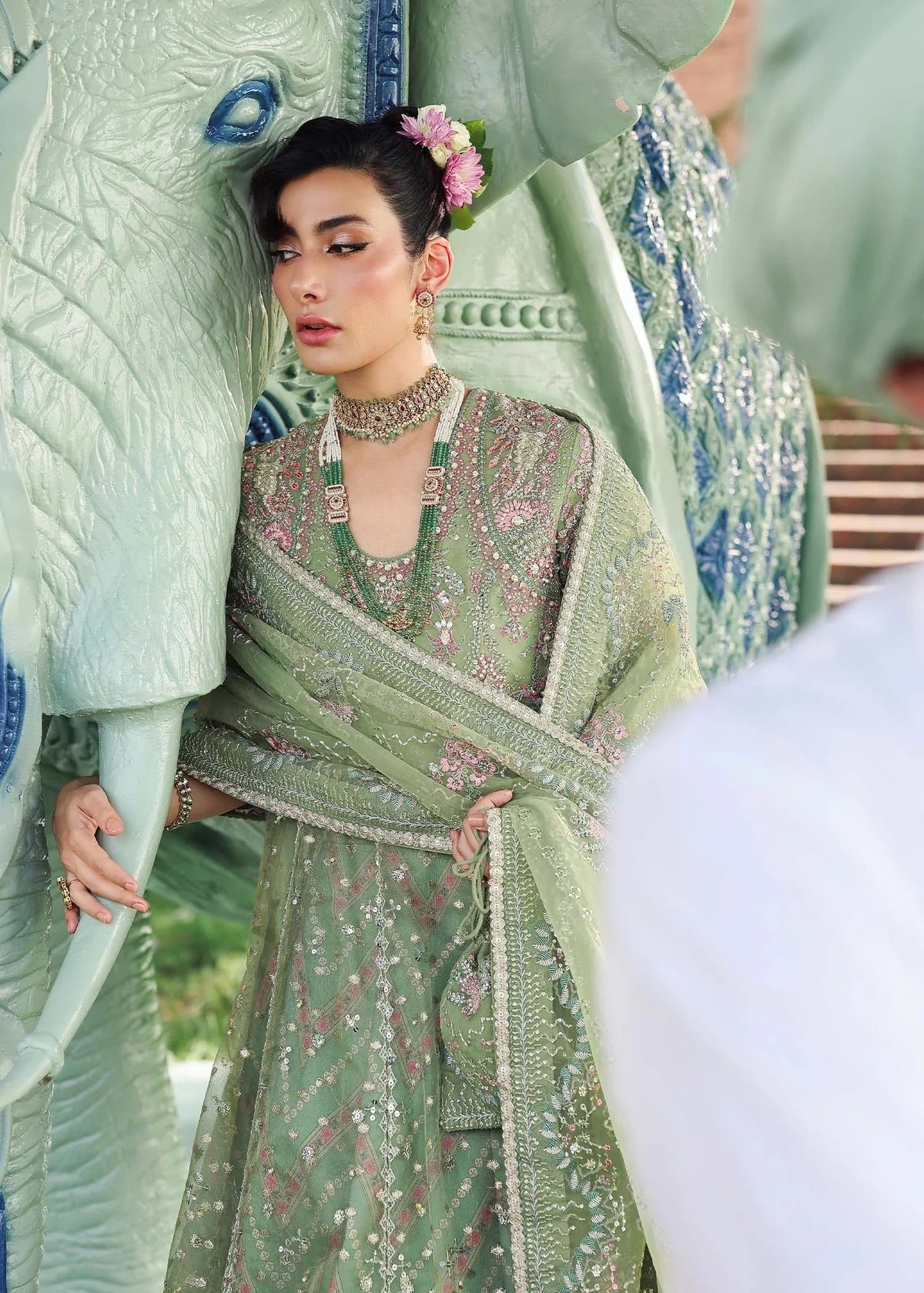 Elevate your festive look with this sage green zari organza outfit featuring delicate hand embroidery, printed raw silk trousers, and an elegant dupatta.