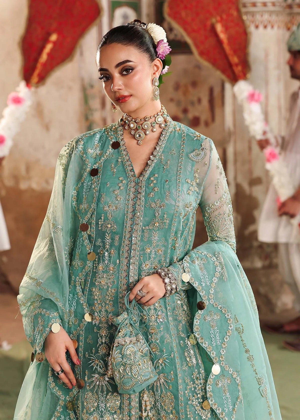 Discover timeless elegance with this turquoise organza outfit featuring intricate hand embroidery, foil-printed raw silk trouser, and embroidered dupatta.