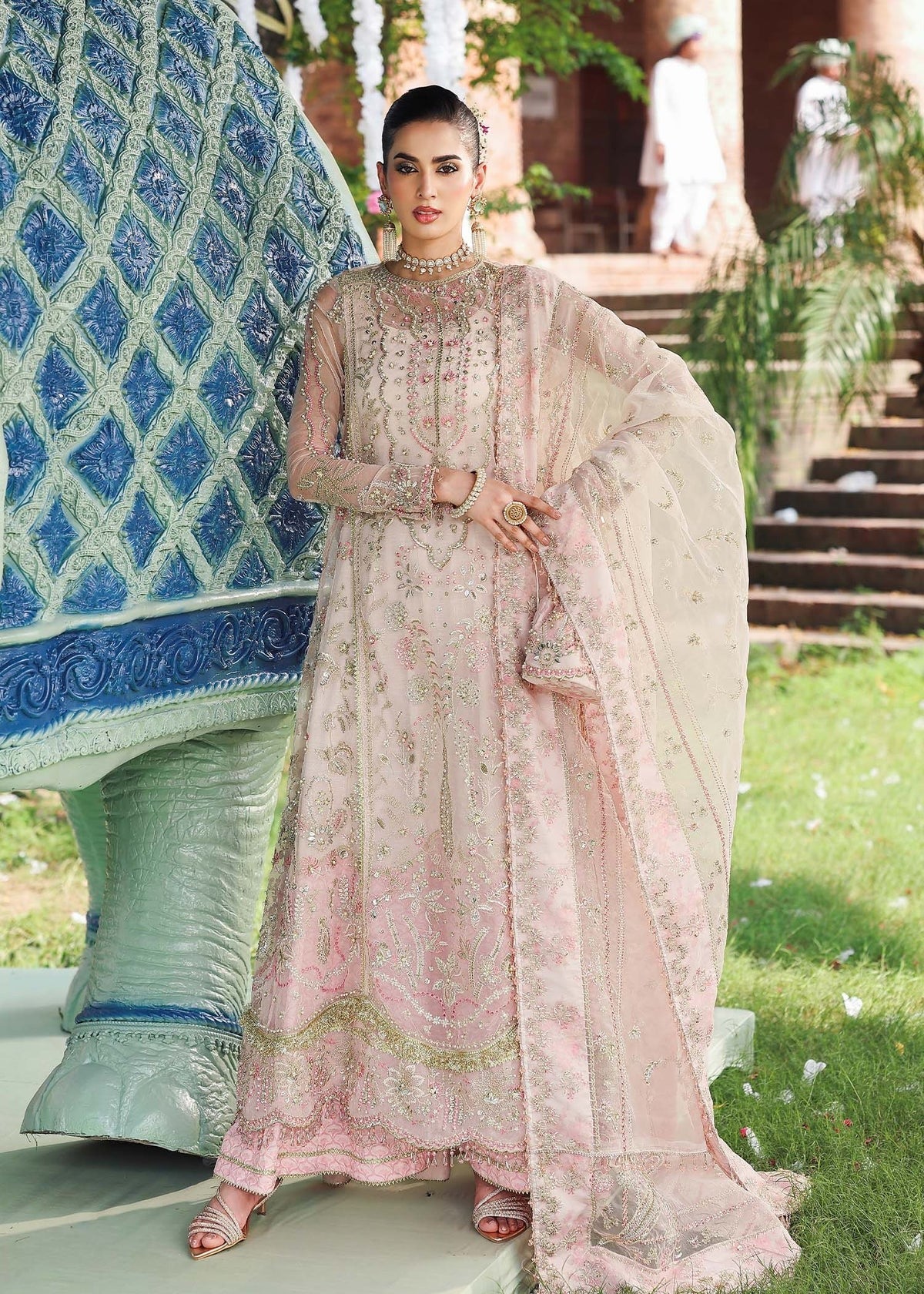 Elevate your style with this light pink organza outfit featuring hand-embroidered panels, dupatta with pallu border, and printed raw silk trouser for a refined look.
