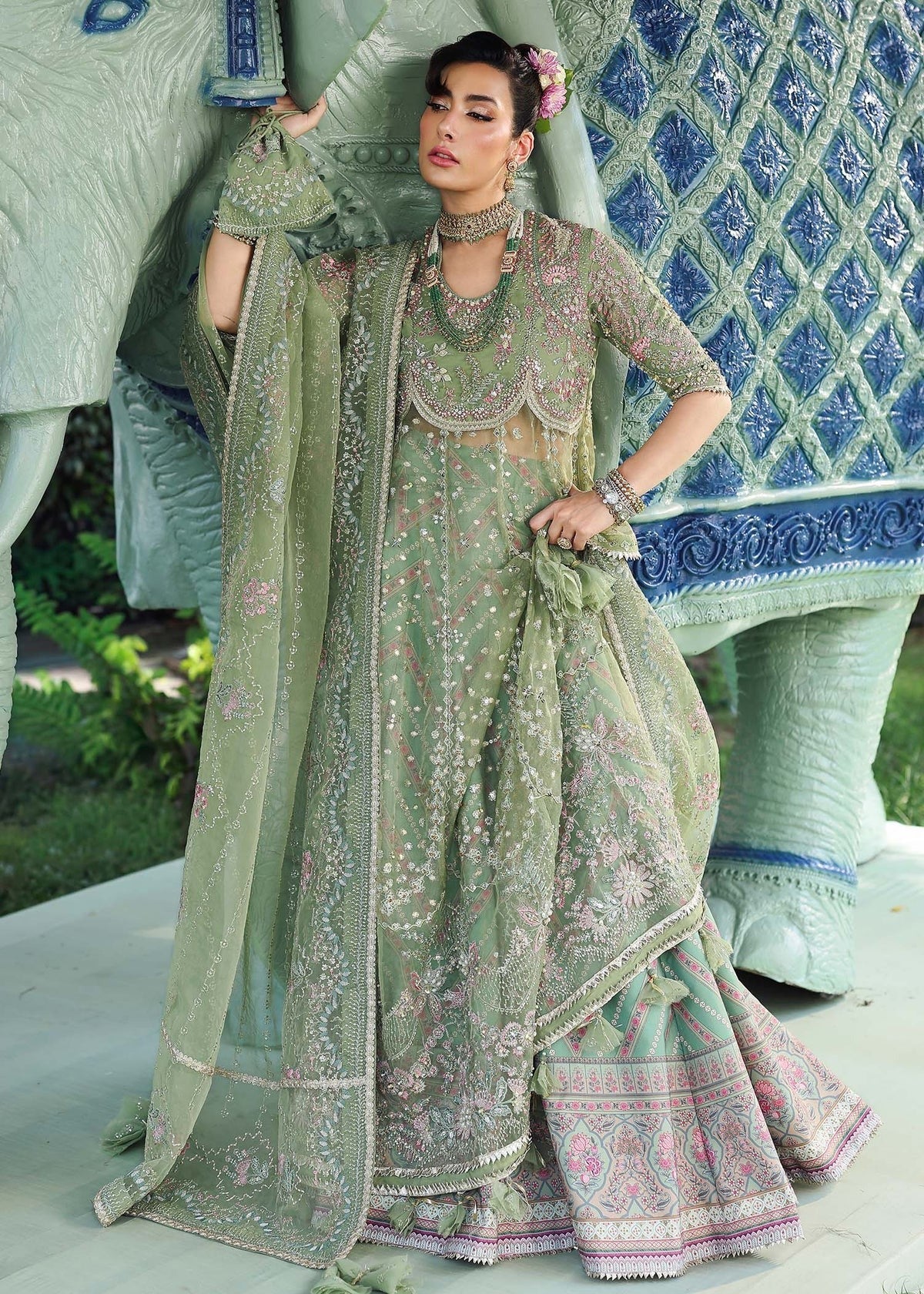 Elevate your festive look with this sage green zari organza outfit featuring delicate hand embroidery, printed raw silk trousers, and an elegant dupatta.