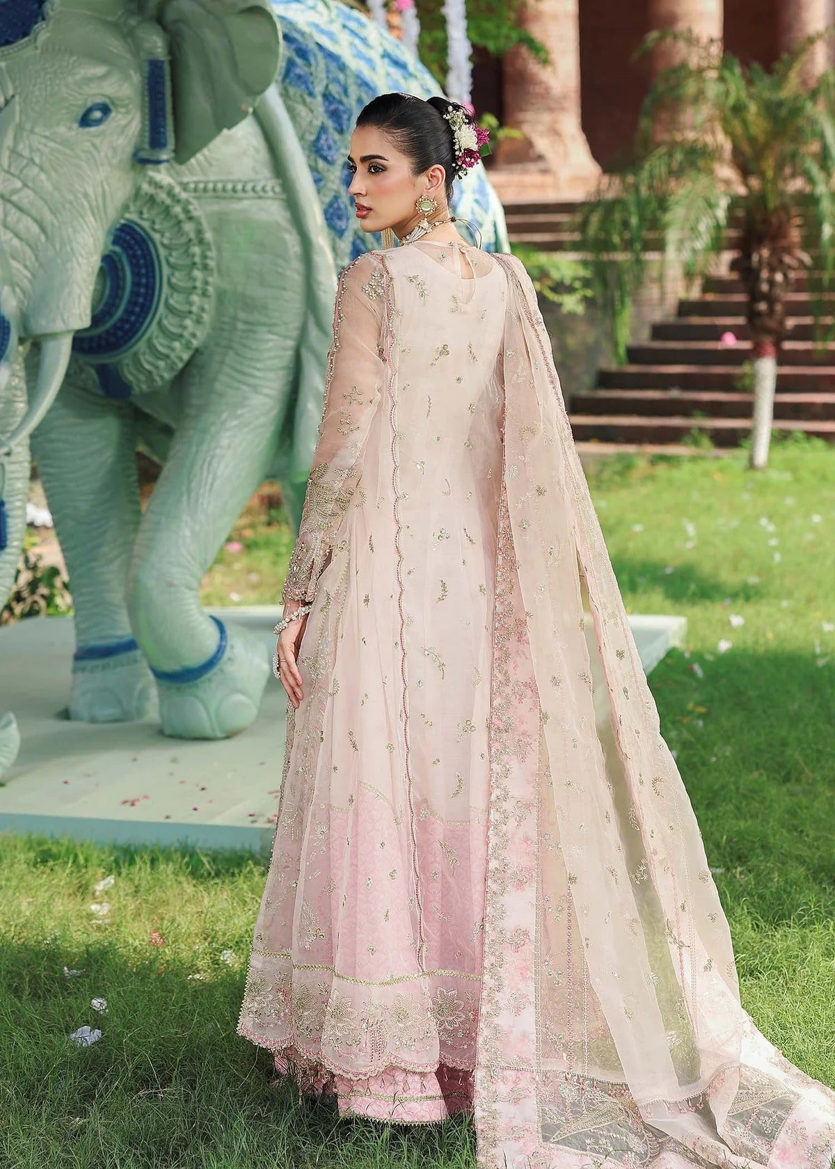 Elevate your style with this light pink organza outfit featuring hand-embroidered panels, dupatta with pallu border, and printed raw silk trouser for a refined look.