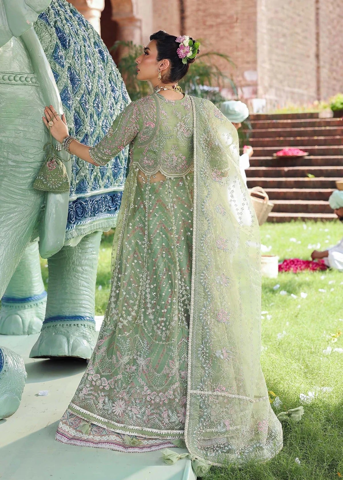 Elevate your festive look with this sage green zari organza outfit featuring delicate hand embroidery, printed raw silk trousers, and an elegant dupatta.