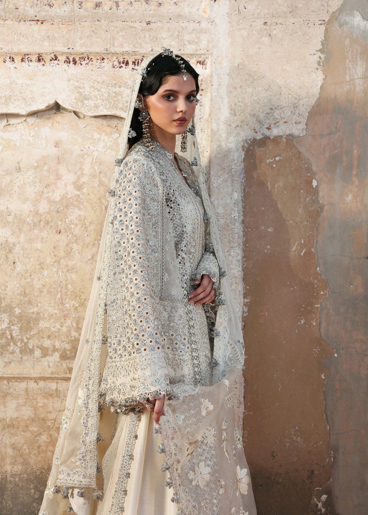 Elegant ivory organza shirt with sequin embroidery, silk sharara, and chiffon dupatta. Unstitched luxury outfit exuding timeless grace and sophistication.