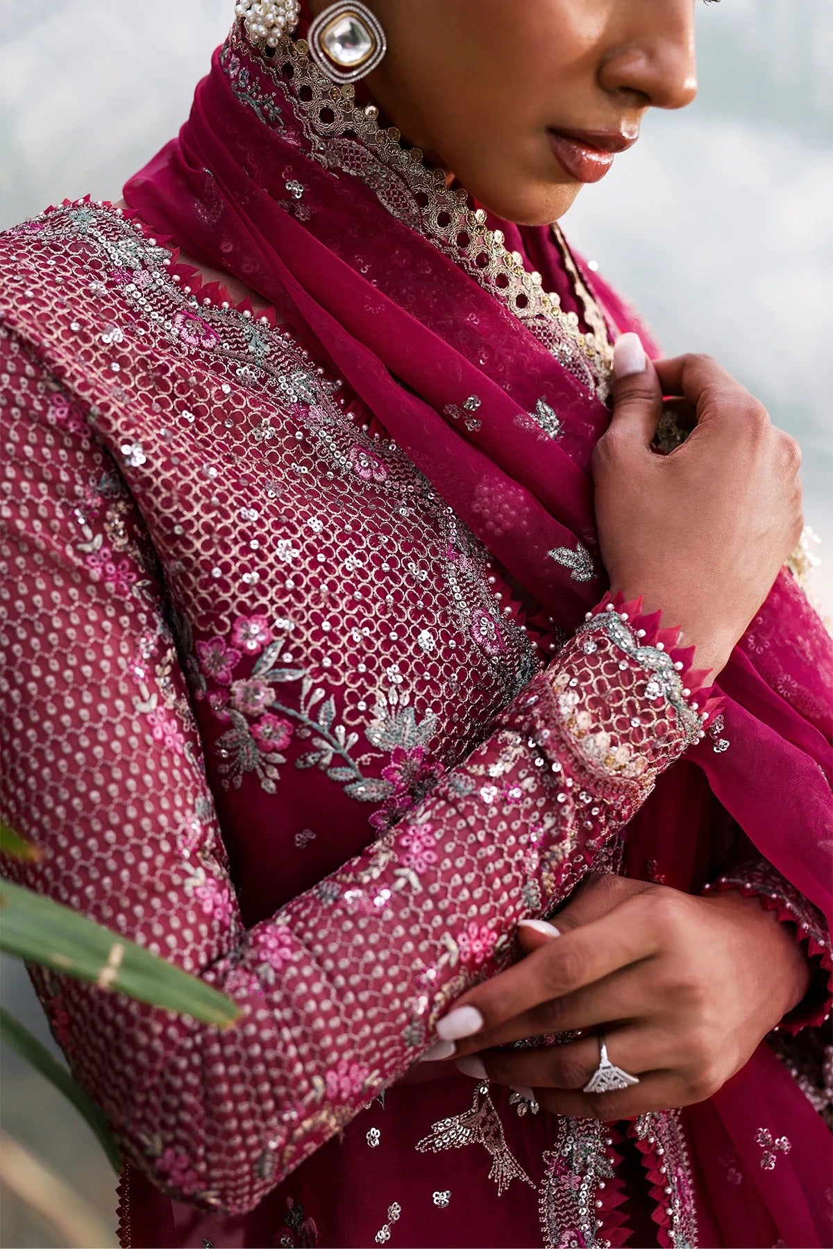Elegant soft pink organza suit with embroidered panels, red accents, silk dupatta borders, and matching raw silk trouser for a refined look.