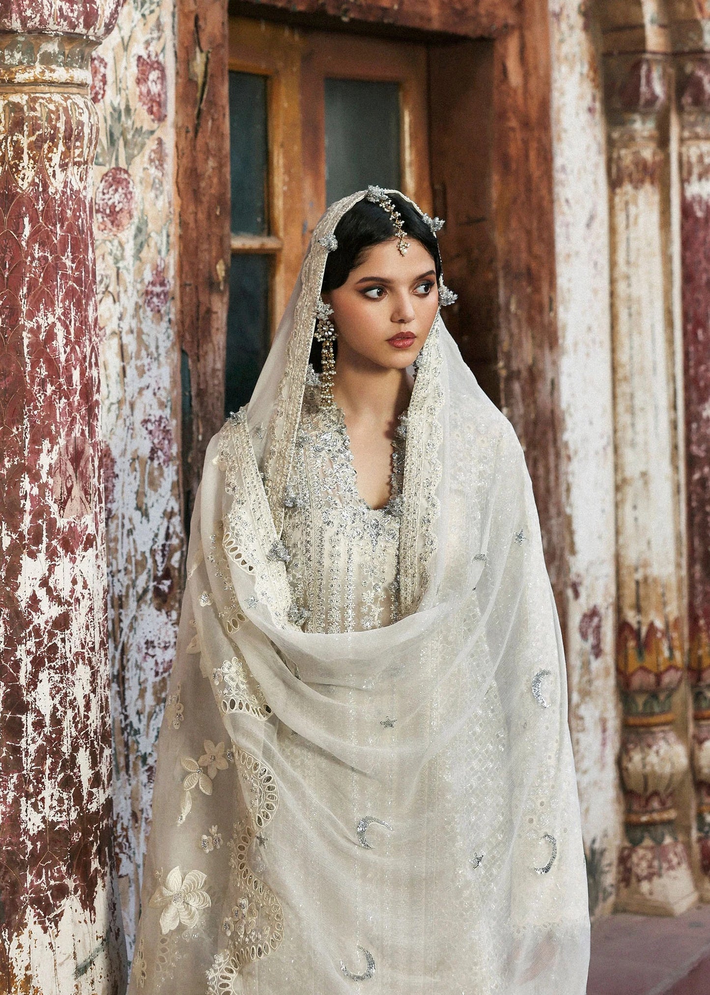 Elegant ivory organza shirt with sequin embroidery, silk sharara, and chiffon dupatta. Unstitched luxury outfit exuding timeless grace and sophistication.