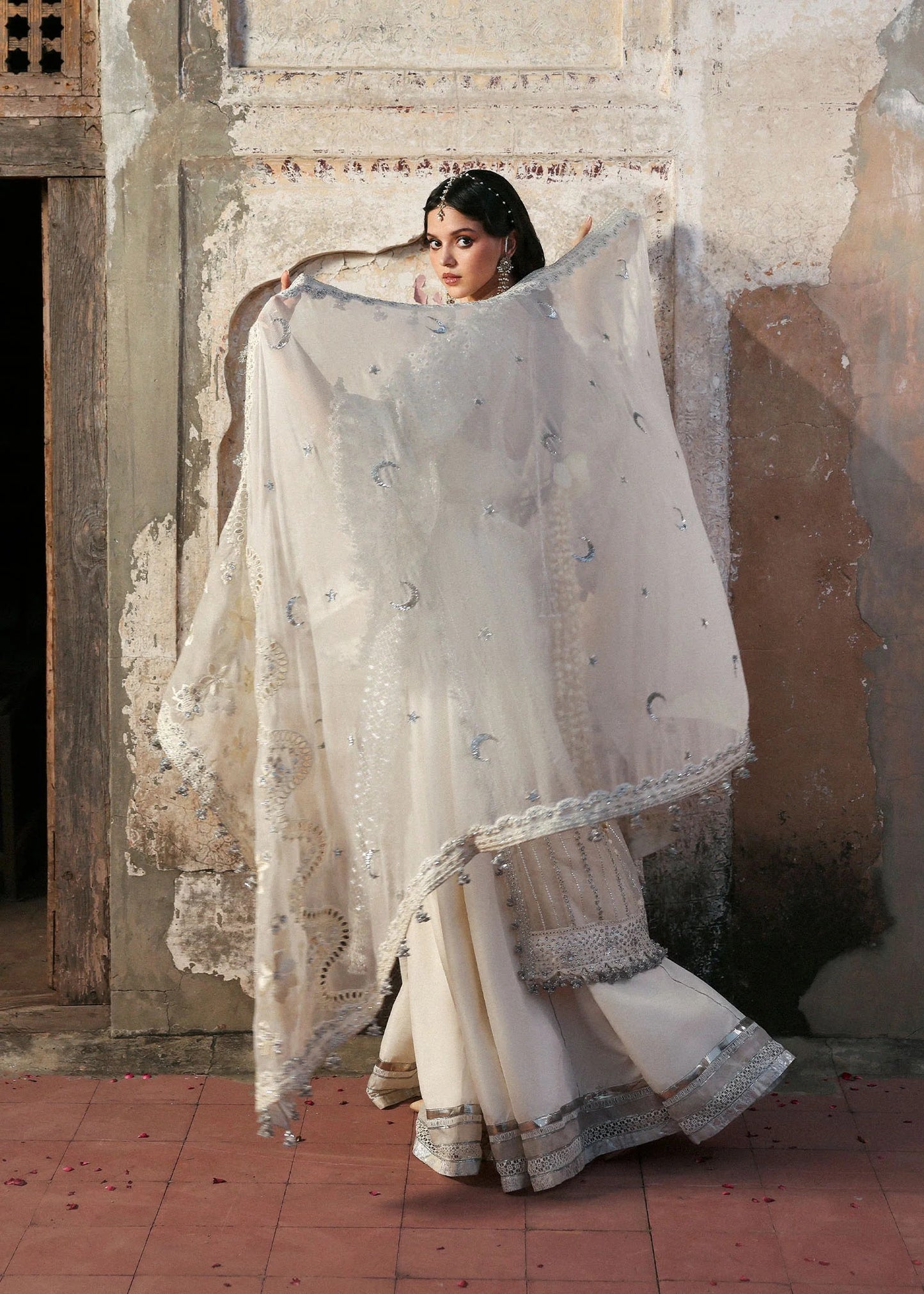 Elegant ivory organza shirt with sequin embroidery, silk sharara, and chiffon dupatta. Unstitched luxury outfit exuding timeless grace and sophistication.