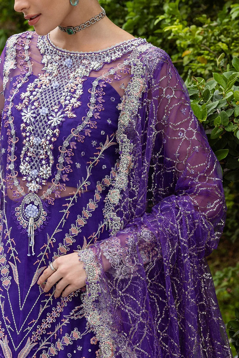 Luxurious purple dress featuring embroidered net shirt, sequined dupatta, raw silk trouser, pearl embellishments, and handmade tassels.