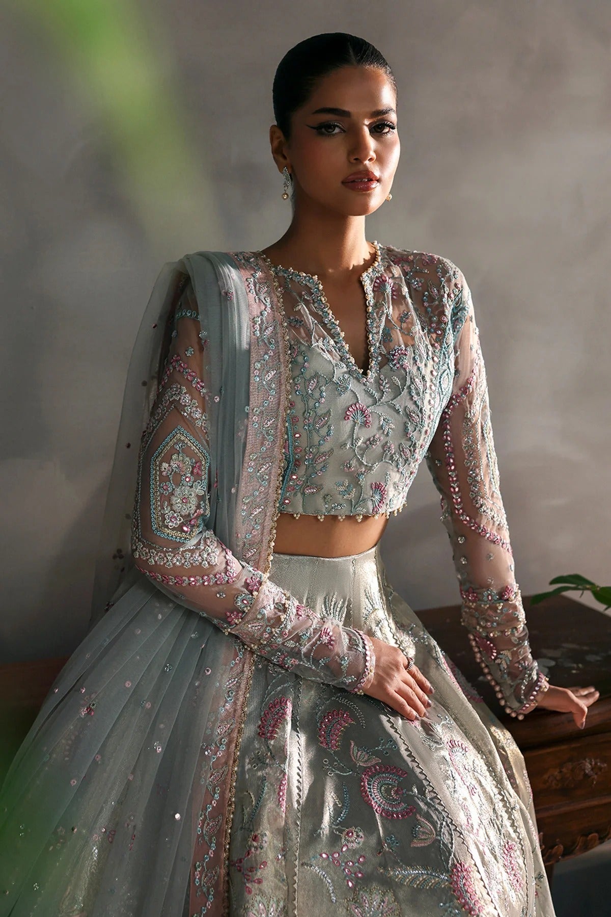 Elegant aqua net dress with intricate zari tissue embroidery in aqua and rose pink. Includes embroidered dupatta, sleeves, and dyed raw silk trouser for grace.