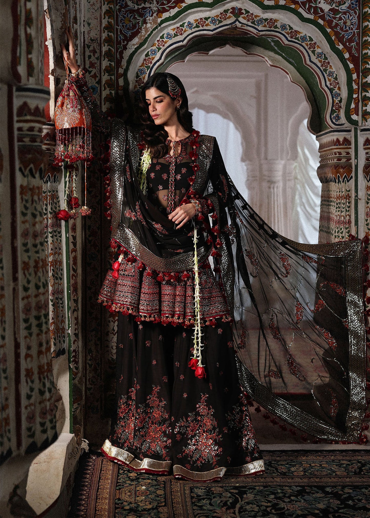 Elegant black embroidered peplum paired with flared Korean raw silk sharara and chiffon dupatta featuring delicate embroidery and four-sided borders for festive events.