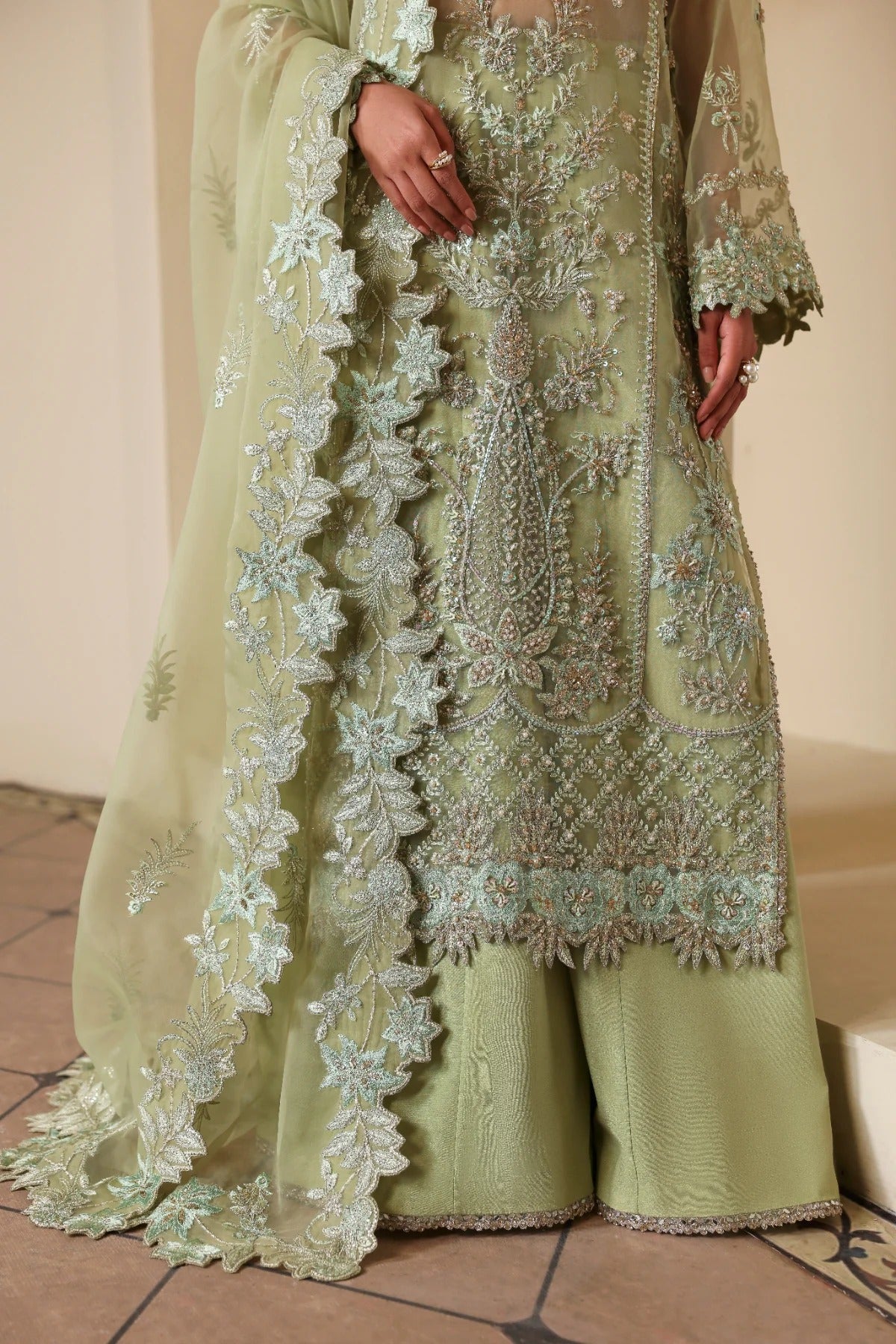 Luxurious organza suit featuring hand-embellished panels, sleeves, borders, and dupatta. Paired with Russian grip inner and 4 yards of raw silk trouser fabric.