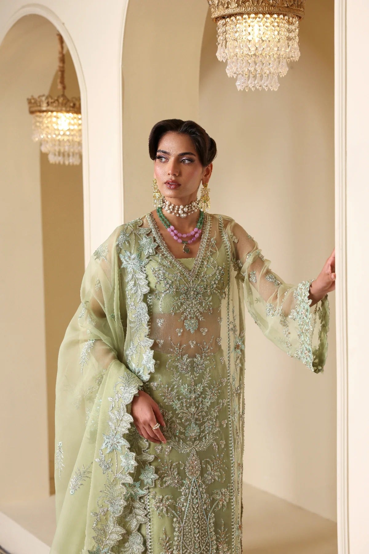 Luxurious organza suit featuring hand-embellished panels, sleeves, borders, and dupatta. Paired with Russian grip inner and 4 yards of raw silk trouser fabric.