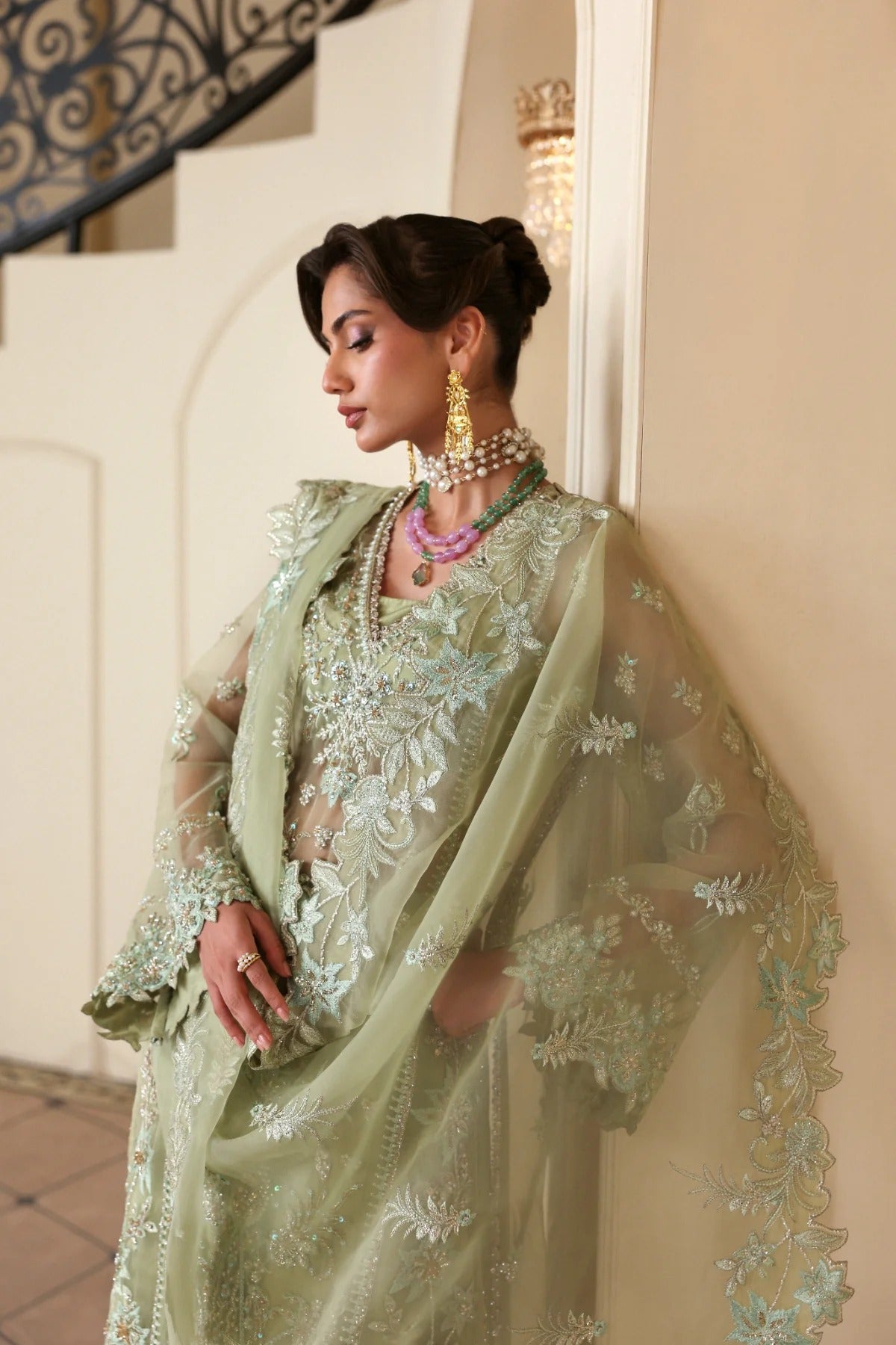 Luxurious organza suit featuring hand-embellished panels, sleeves, borders, and dupatta. Paired with Russian grip inner and 4 yards of raw silk trouser fabric.