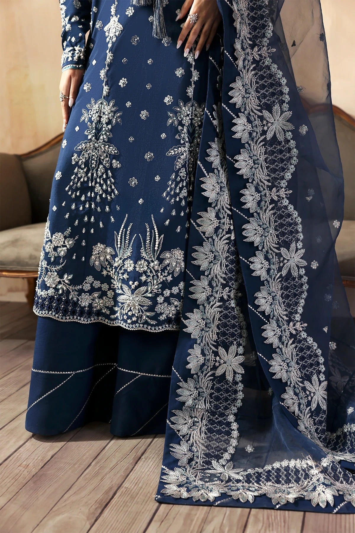 Luxury hand-embroidered raw silk suit with detailed front, back, and sleeves panels, paired with an elegant organza dupatta and matching dyed silk trousers—perfect for festive occasions.