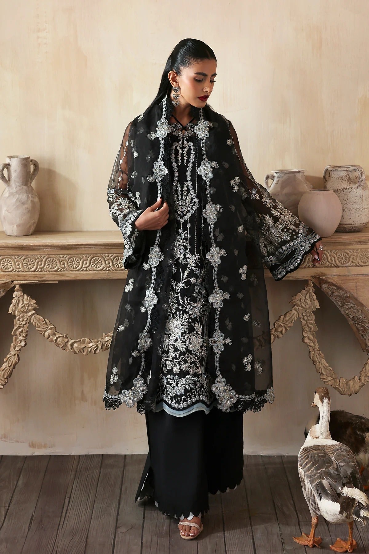 Elegant hand-embroidered organza suit with detailed front, back, and sleeves panels, paired with a matching organza dupatta and dyed trousers—perfect for festive occasions.