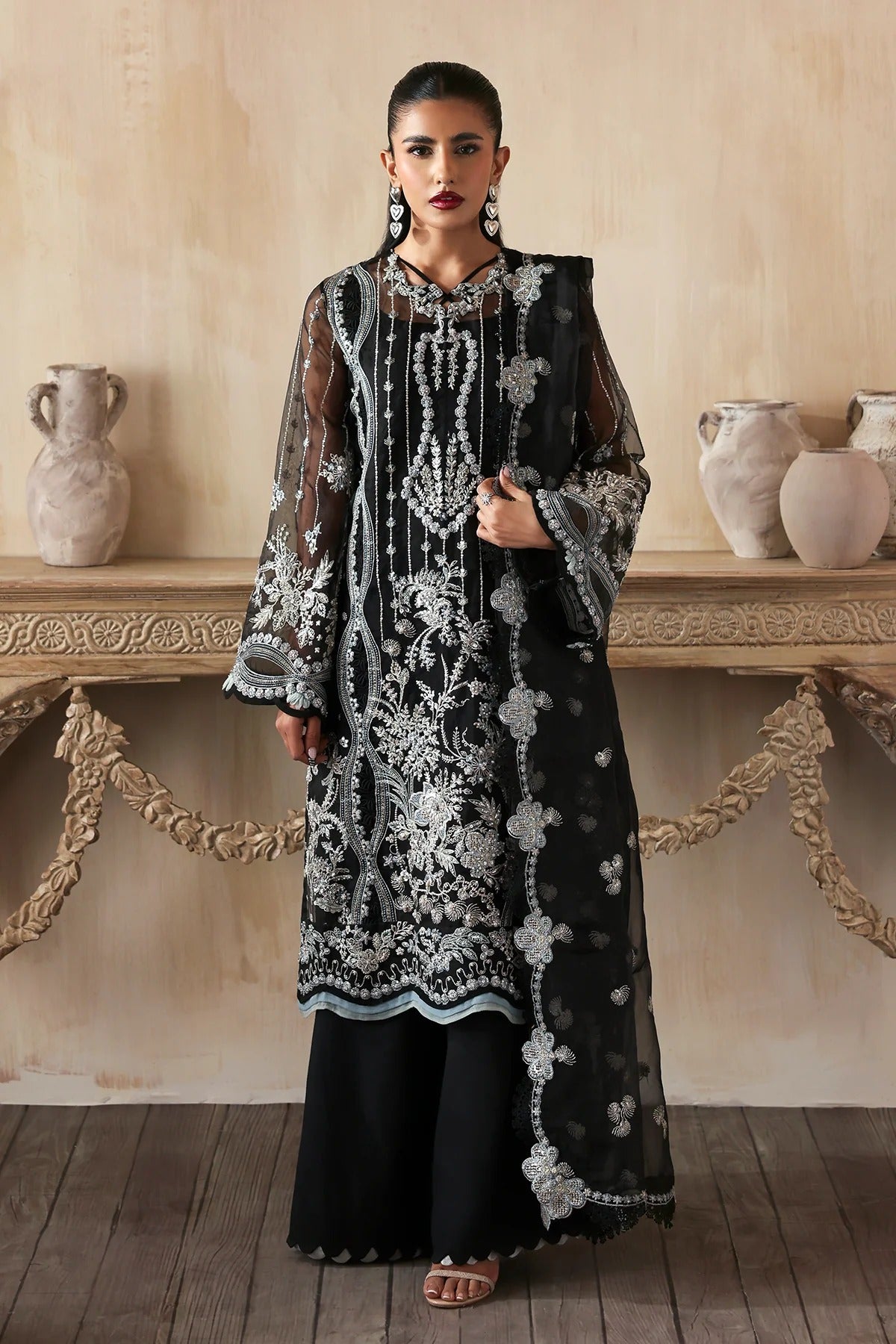 Elegant hand-embroidered organza suit with detailed front, back, and sleeves panels, paired with a matching organza dupatta and dyed trousers—perfect for festive occasions.
