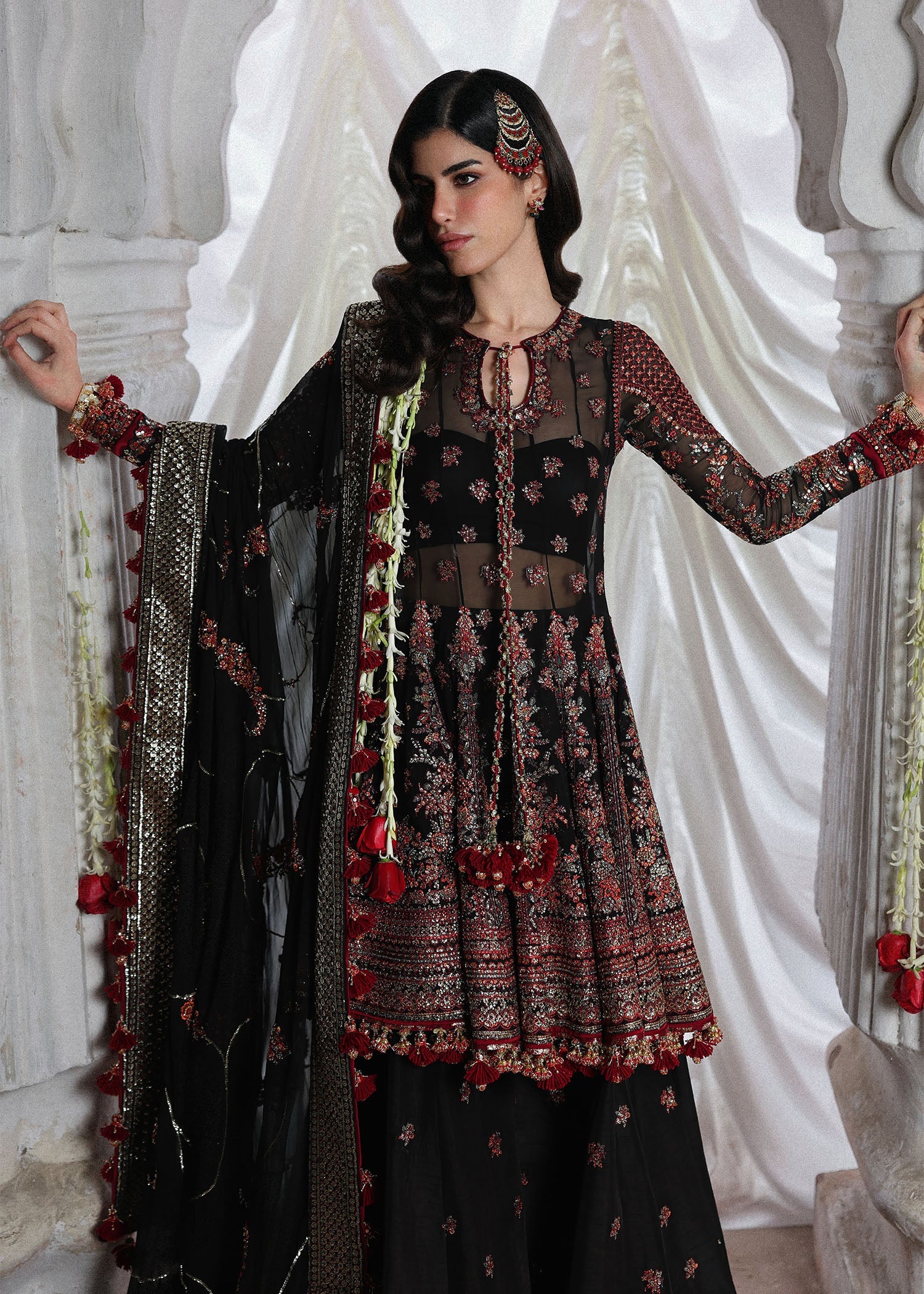 Elegant black embroidered peplum paired with flared Korean raw silk sharara and chiffon dupatta featuring delicate embroidery and four-sided borders for festive events.