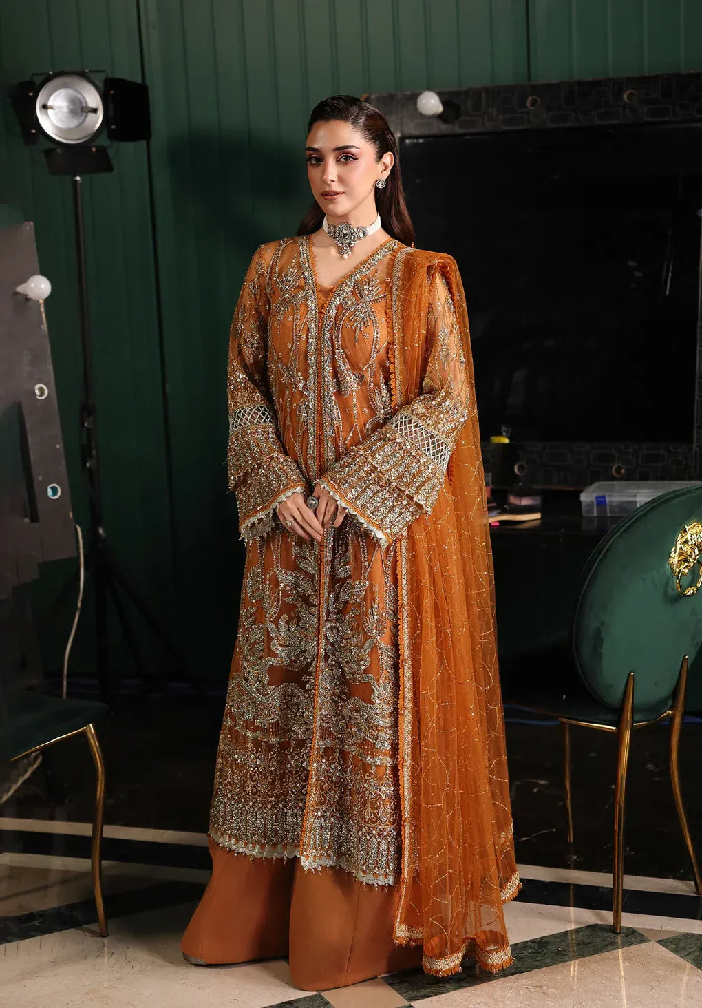 Saffron from Elaf Stardom ’25 features hand-embellished poly-net panels, embroidered dupatta, and raw silk inner — a graceful choice for festive elegance.