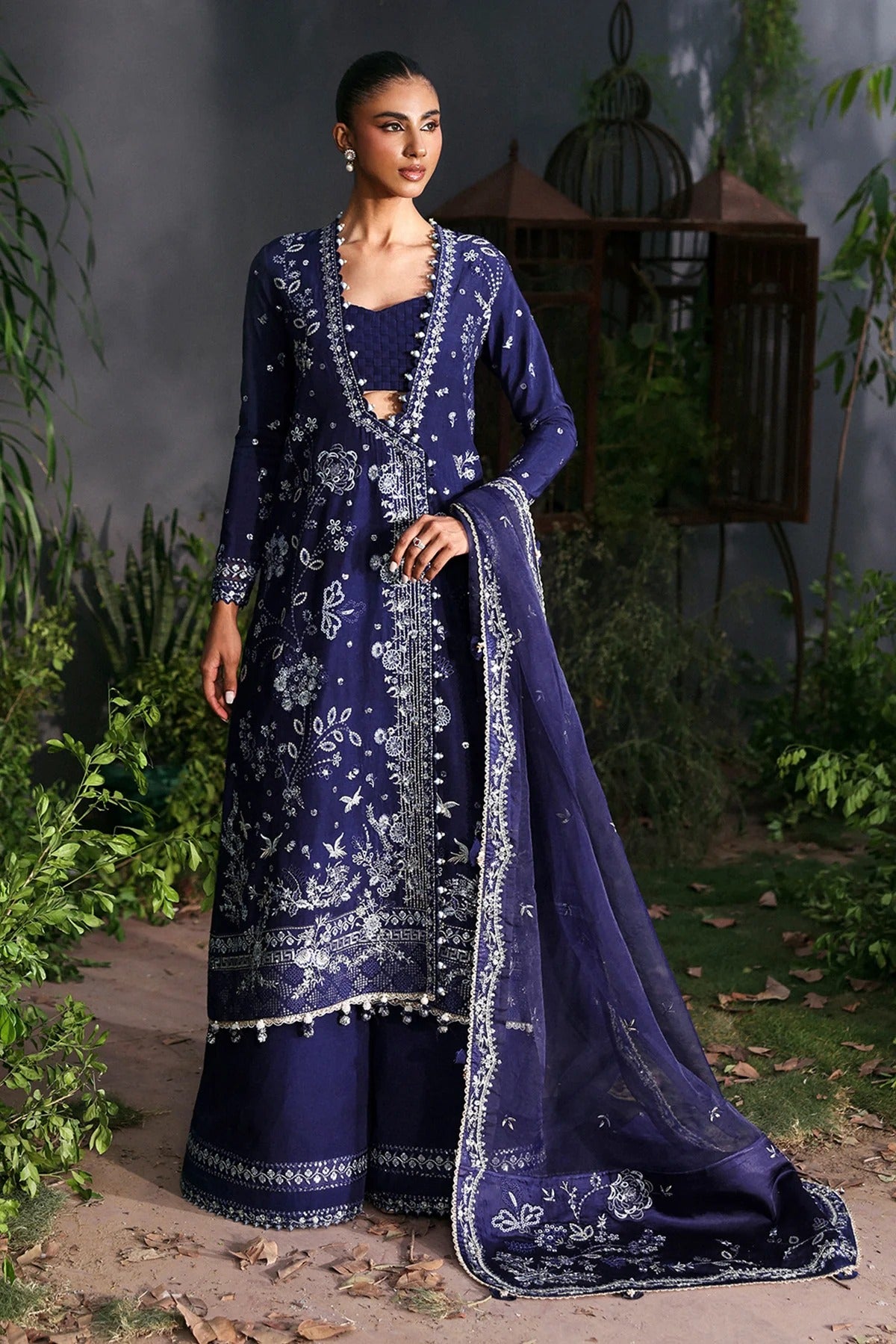 Elegant blue raw silk dress featuring intricate embroidery, organza dupatta, shmoze silk borders, and dyed trousers. Perfect for festive or formal wear.