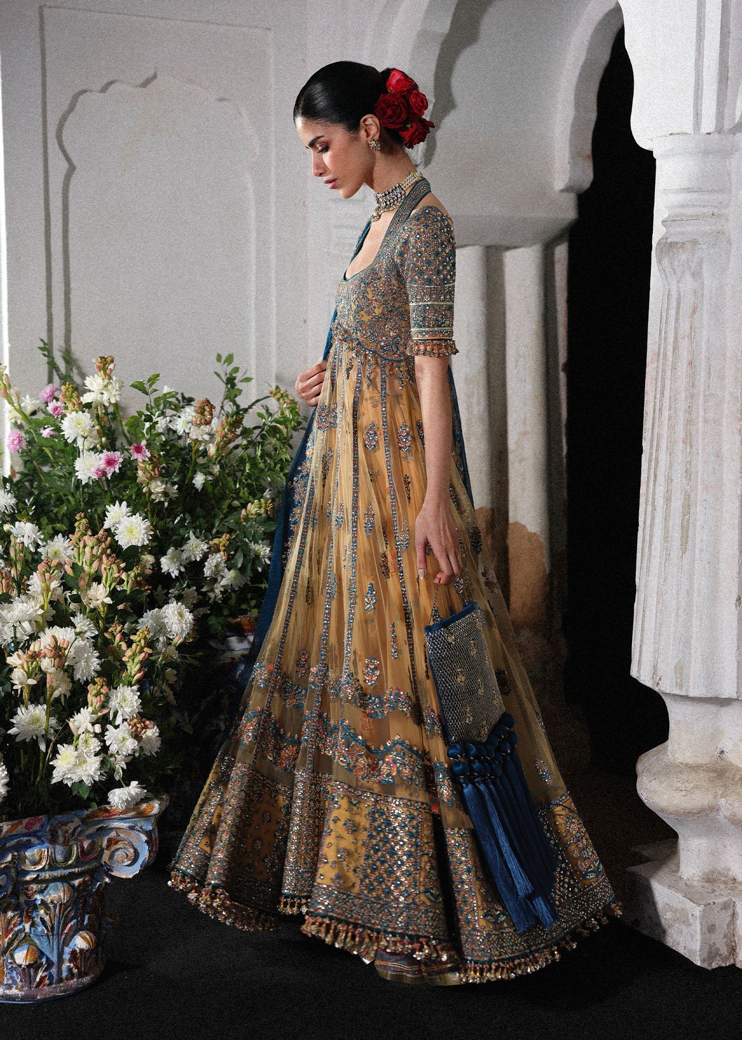 Graceful butter yellow net pishwas with embroidered panels and sleeves, paired with printed Korean raw silk sharara and a chiffon dupatta with borders.