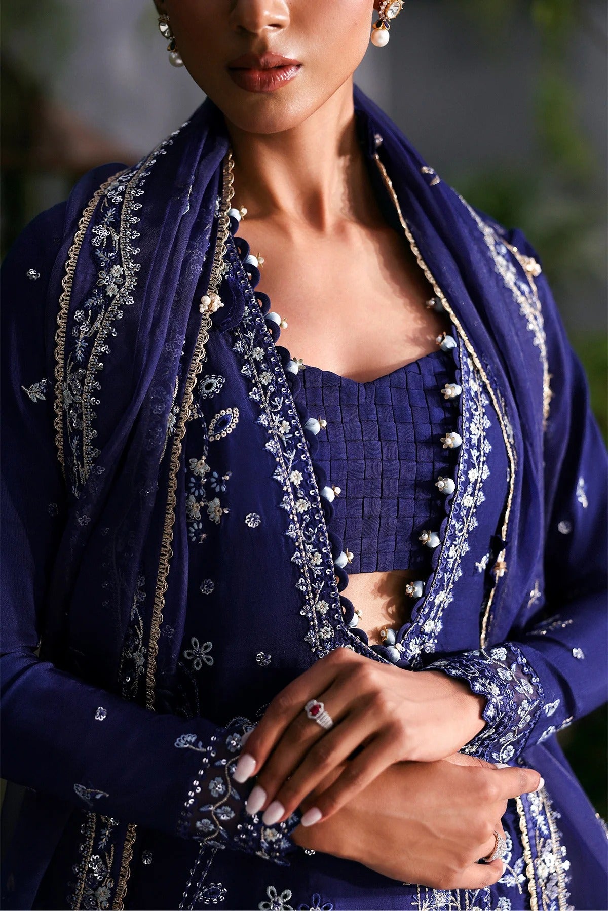 Elegant blue raw silk dress featuring intricate embroidery, organza dupatta, shmoze silk borders, and dyed trousers. Perfect for festive or formal wear.