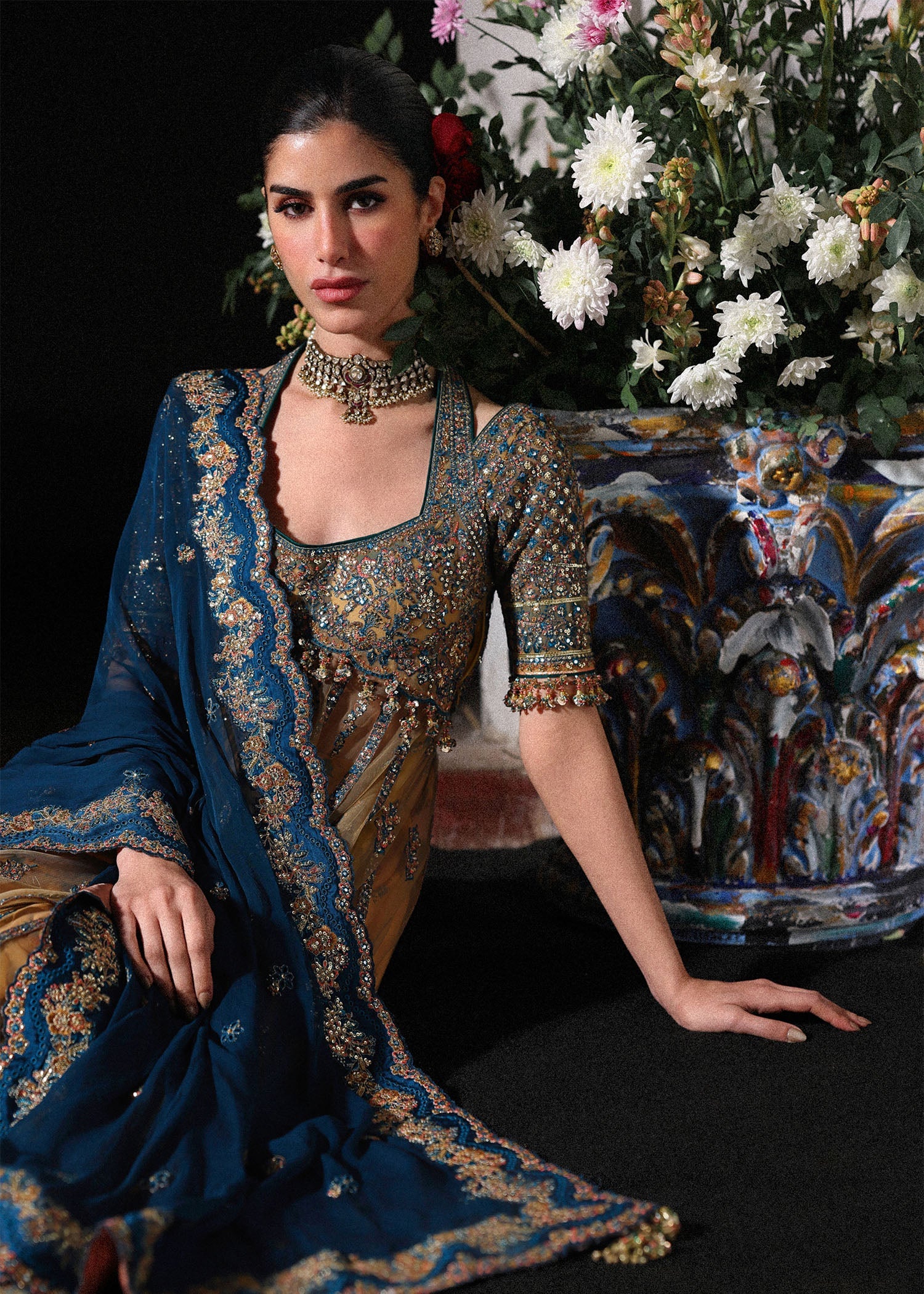Graceful butter yellow net pishwas with embroidered panels and sleeves, paired with printed Korean raw silk sharara and a chiffon dupatta with borders.