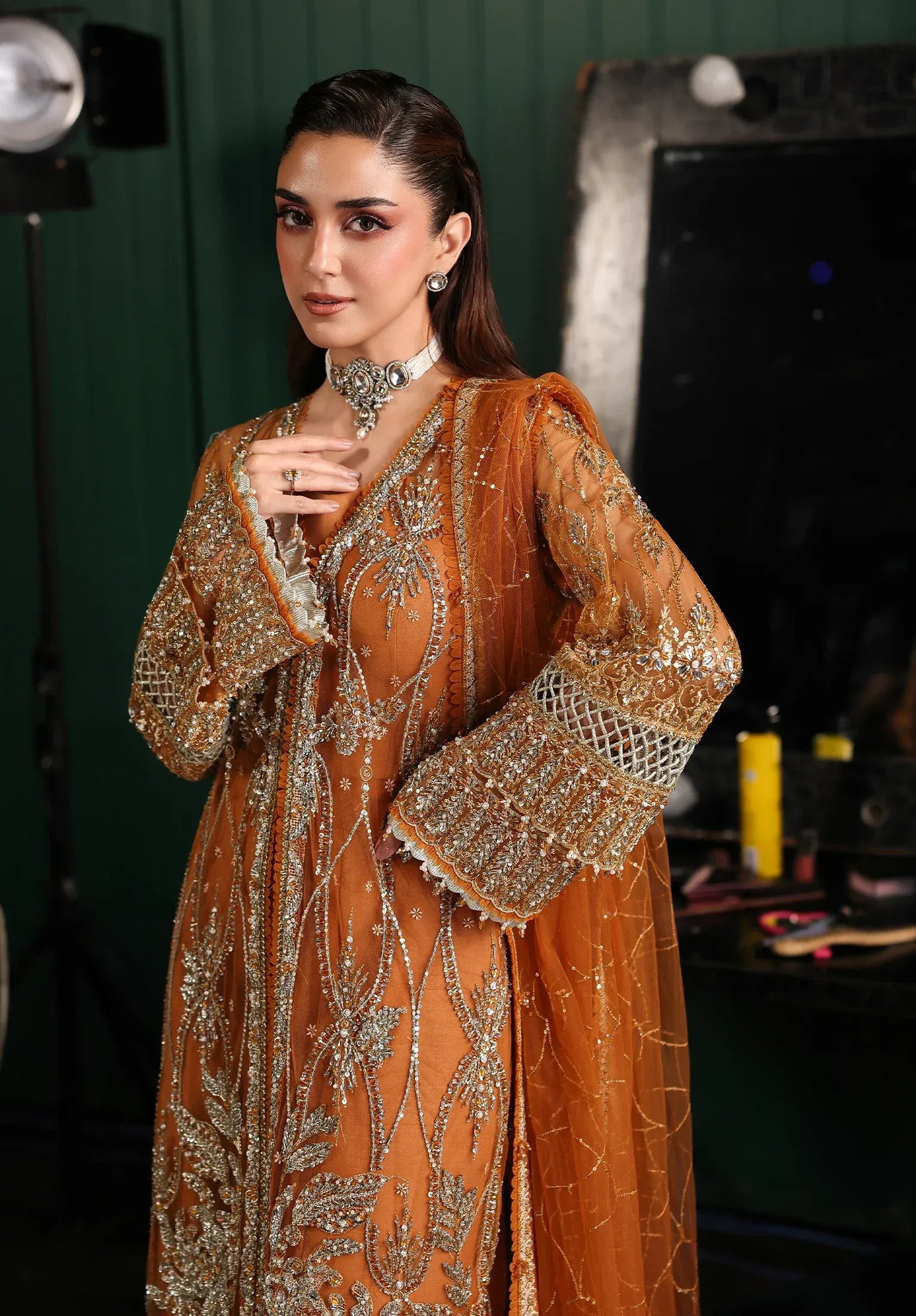 Saffron from Elaf Stardom ’25 features hand-embellished poly-net panels, embroidered dupatta, and raw silk inner — a graceful choice for festive elegance.