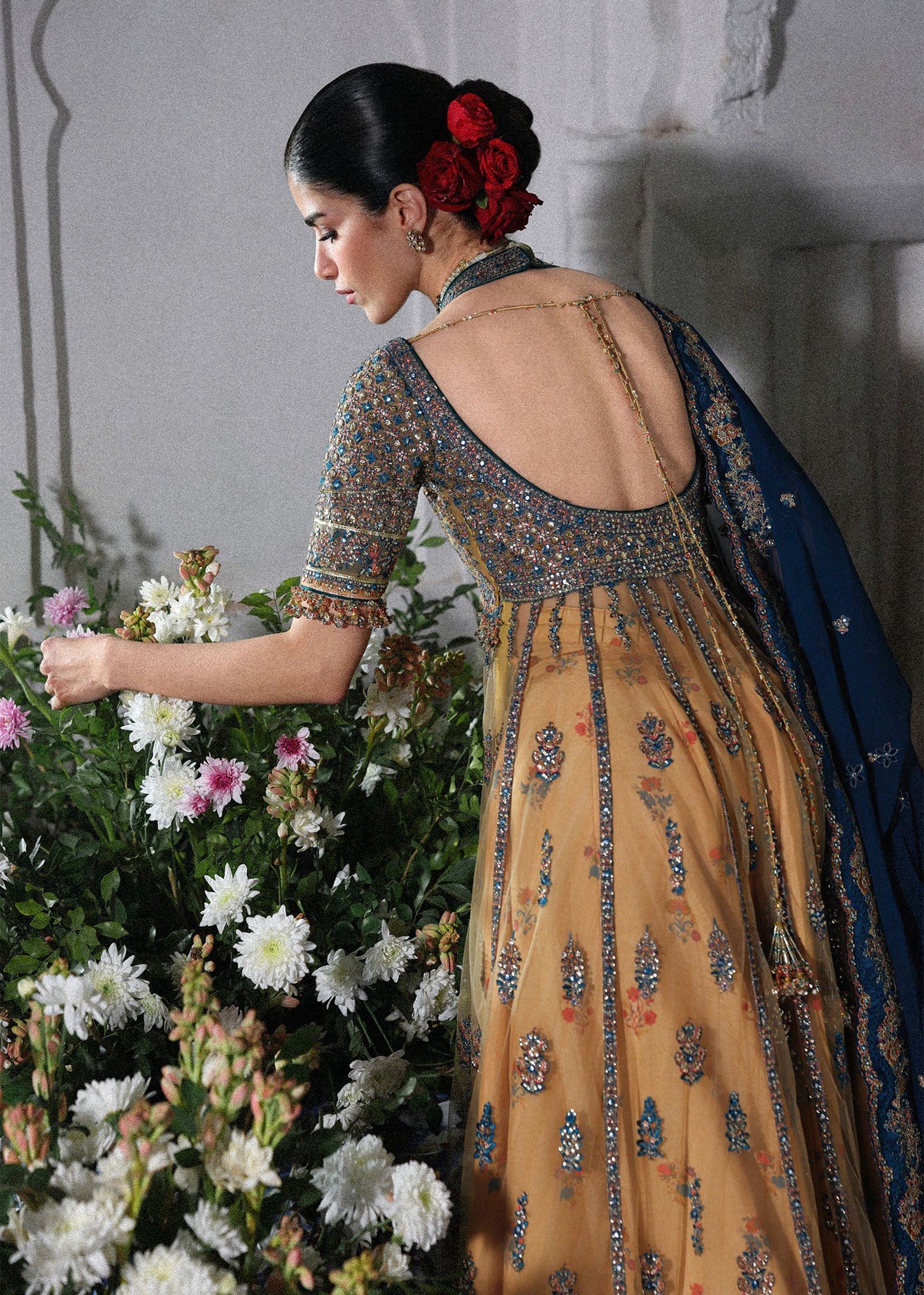 Graceful butter yellow net pishwas with embroidered panels and sleeves, paired with printed Korean raw silk sharara and a chiffon dupatta with borders.