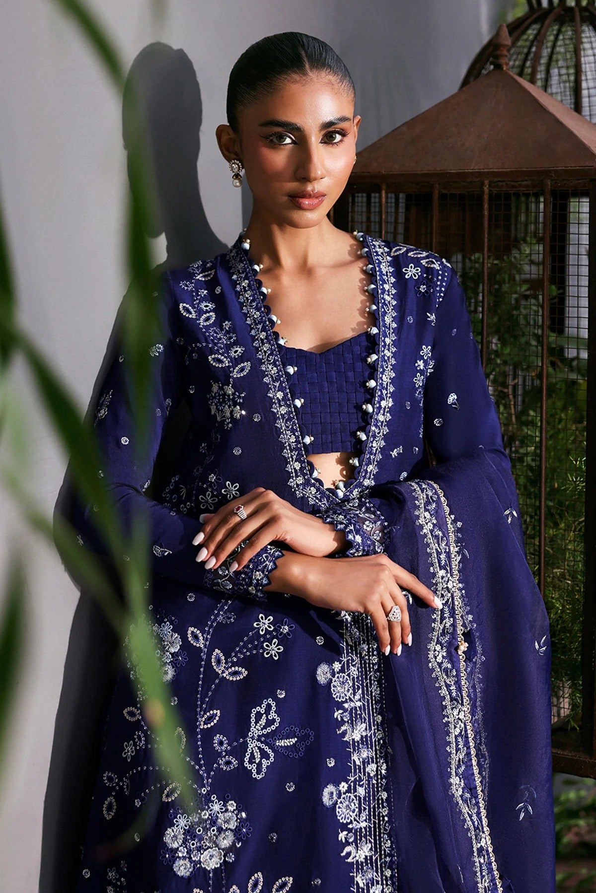 Elegant blue raw silk dress featuring intricate embroidery, organza dupatta, shmoze silk borders, and dyed trousers. Perfect for festive or formal wear.