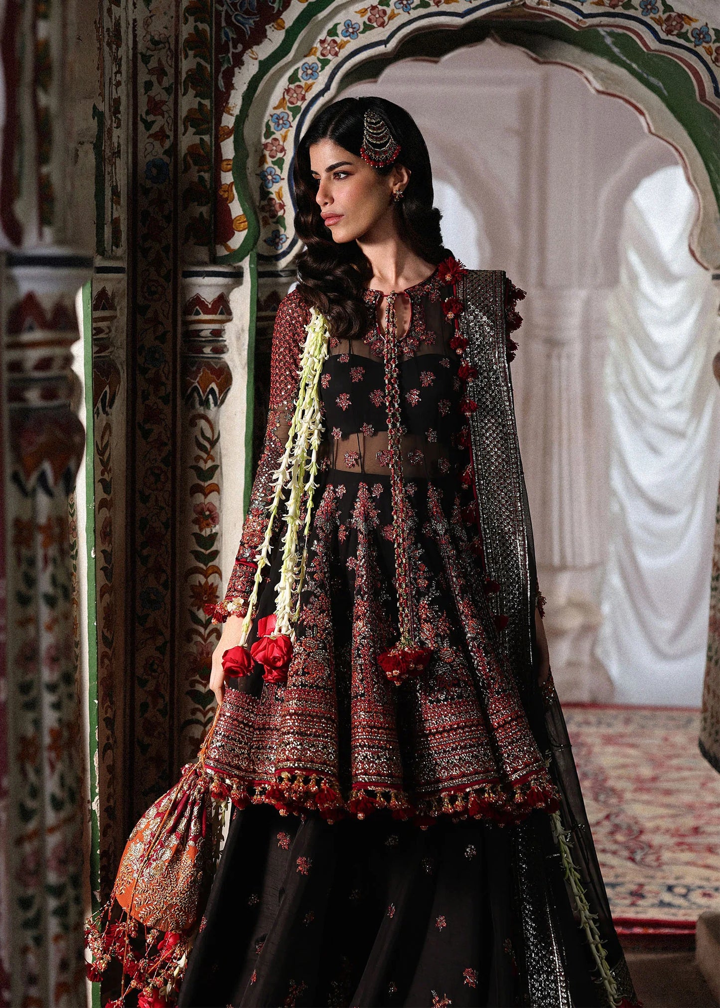 Elegant black embroidered peplum paired with flared Korean raw silk sharara and chiffon dupatta featuring delicate embroidery and four-sided borders for festive events.