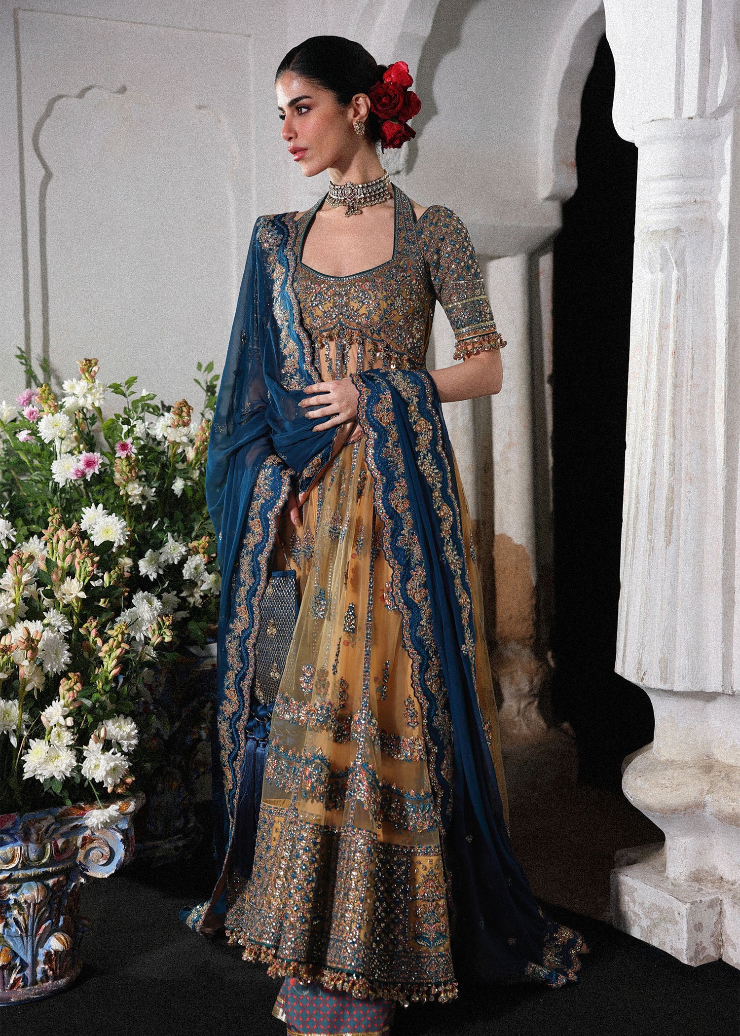 Graceful butter yellow net pishwas with embroidered panels and sleeves, paired with printed Korean raw silk sharara and a chiffon dupatta with borders.