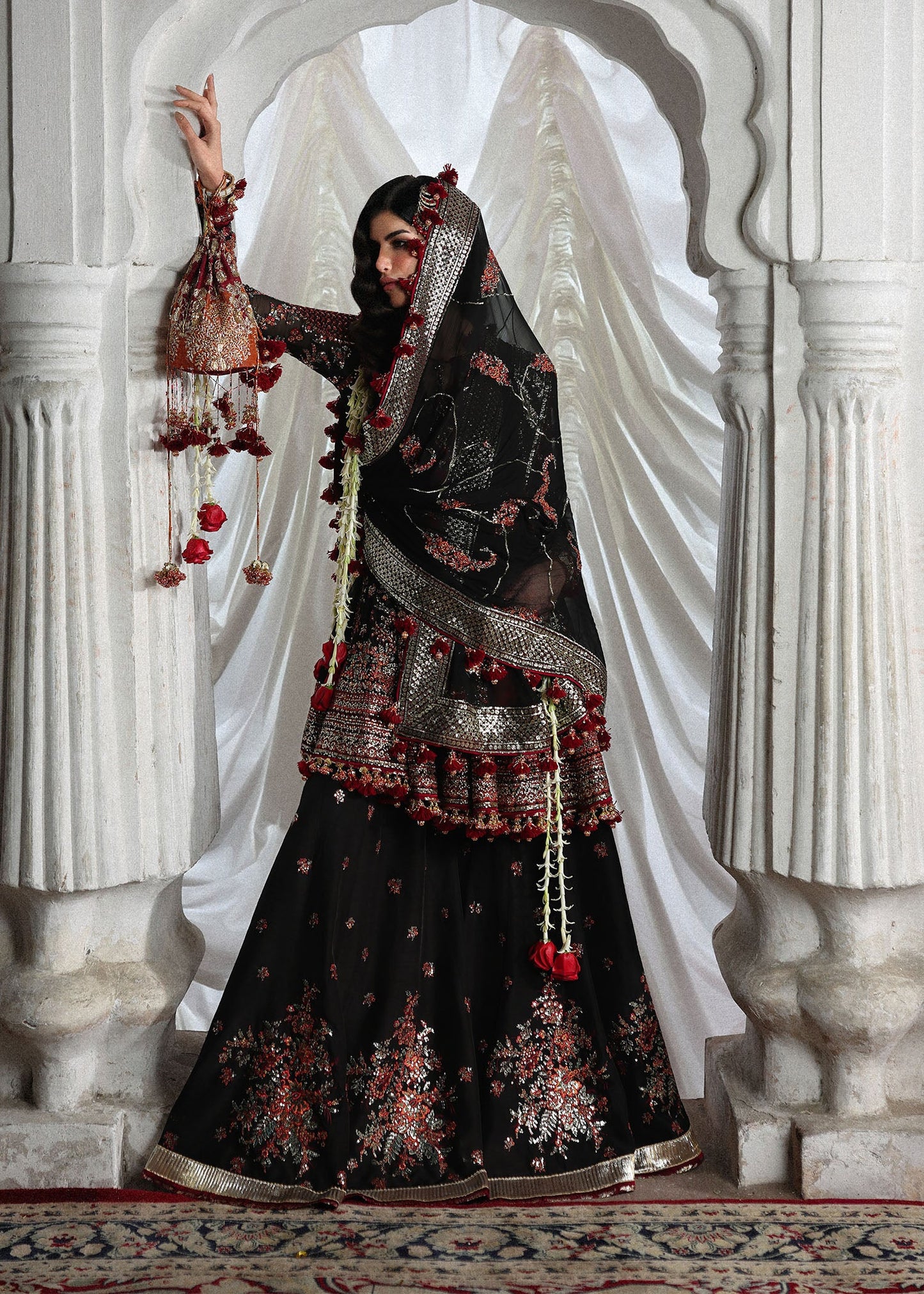 Elegant black embroidered peplum paired with flared Korean raw silk sharara and chiffon dupatta featuring delicate embroidery and four-sided borders for festive events.