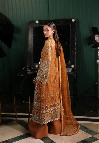 Saffron from Elaf Stardom ’25 features hand-embellished poly-net panels, embroidered dupatta, and raw silk inner — a graceful choice for festive elegance.