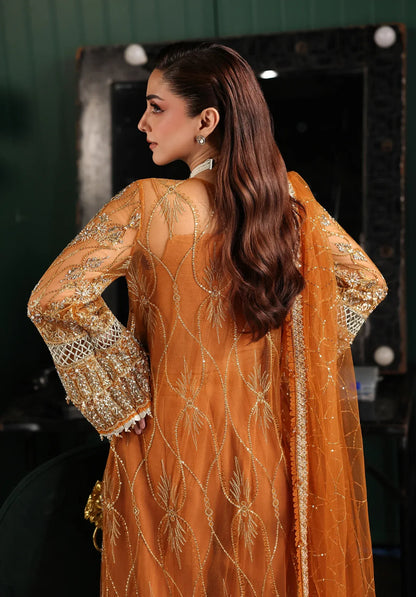 Saffron from Elaf Stardom ’25 features hand-embellished poly-net panels, embroidered dupatta, and raw silk inner — a graceful choice for festive elegance.