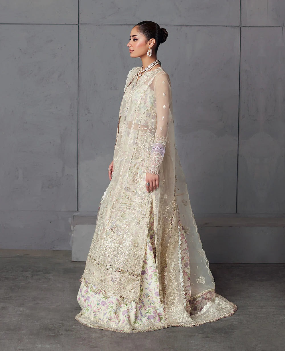 Edera exudes purity in white with hand-embellished organza panels, lilac-pink florals, and a scalloped embroidered dupatta — a vision of grace and artistry.