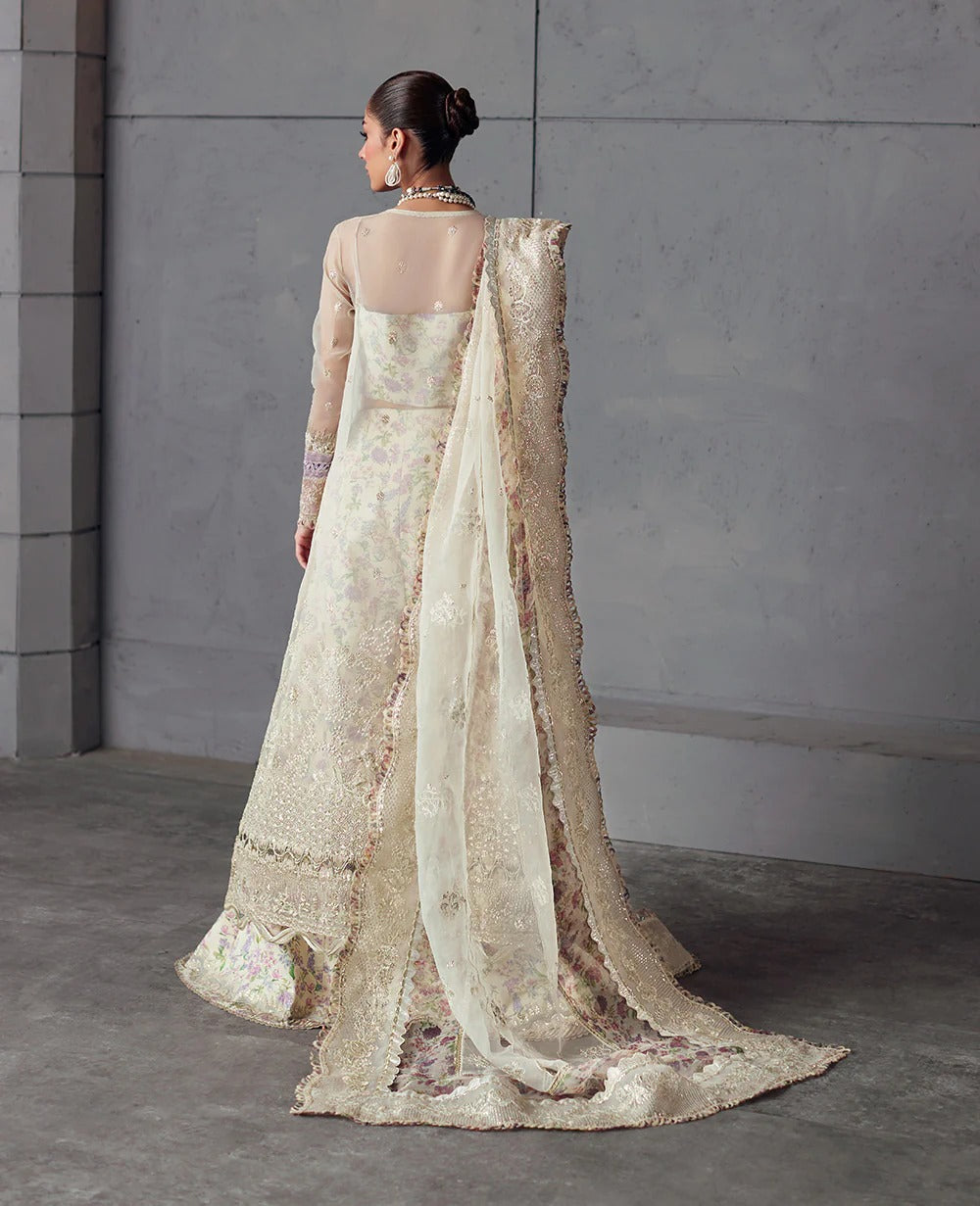 Edera exudes purity in white with hand-embellished organza panels, lilac-pink florals, and a scalloped embroidered dupatta — a vision of grace and artistry.