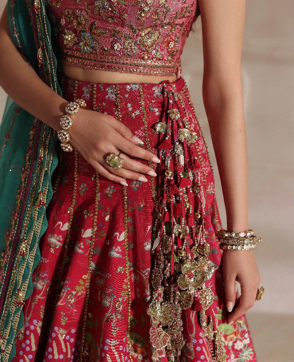 Radiant hot pink raw silk lehenga with a shikargah blouse, golden adda work, and teal embroidered dupatta — a bold, regal blend of color, craft, and heritage.
