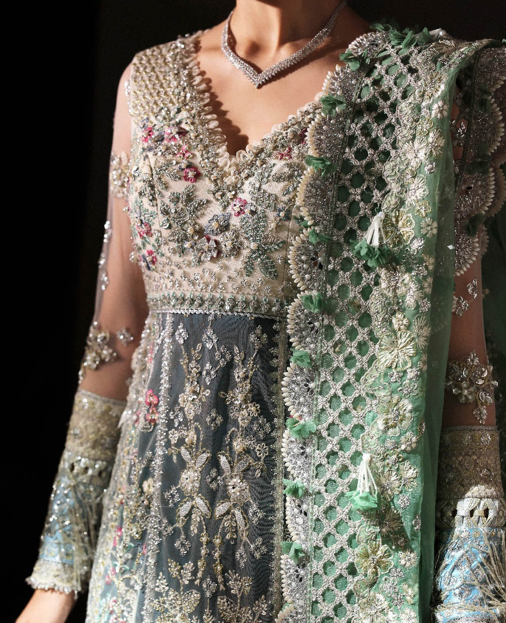 Ethereal white net shirt with blush florals, sequin accents, and a sage dupatta paired with a green lehenga — a perfect blend of grace, charm, and celebration