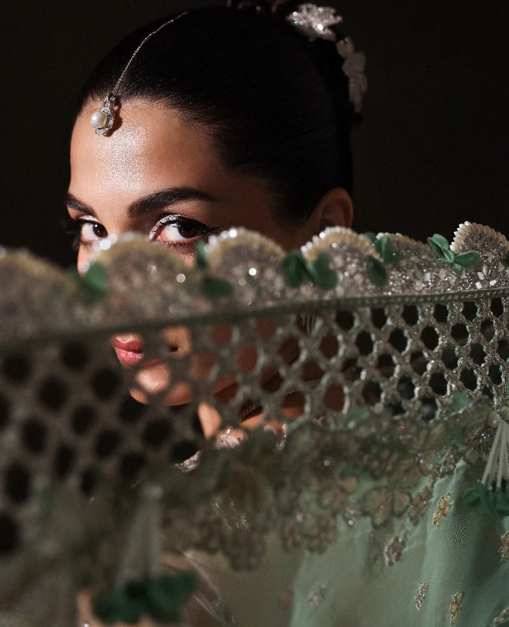 Ethereal white net shirt with blush florals, sequin accents, and a sage dupatta paired with a green lehenga — a perfect blend of grace, charm, and celebration