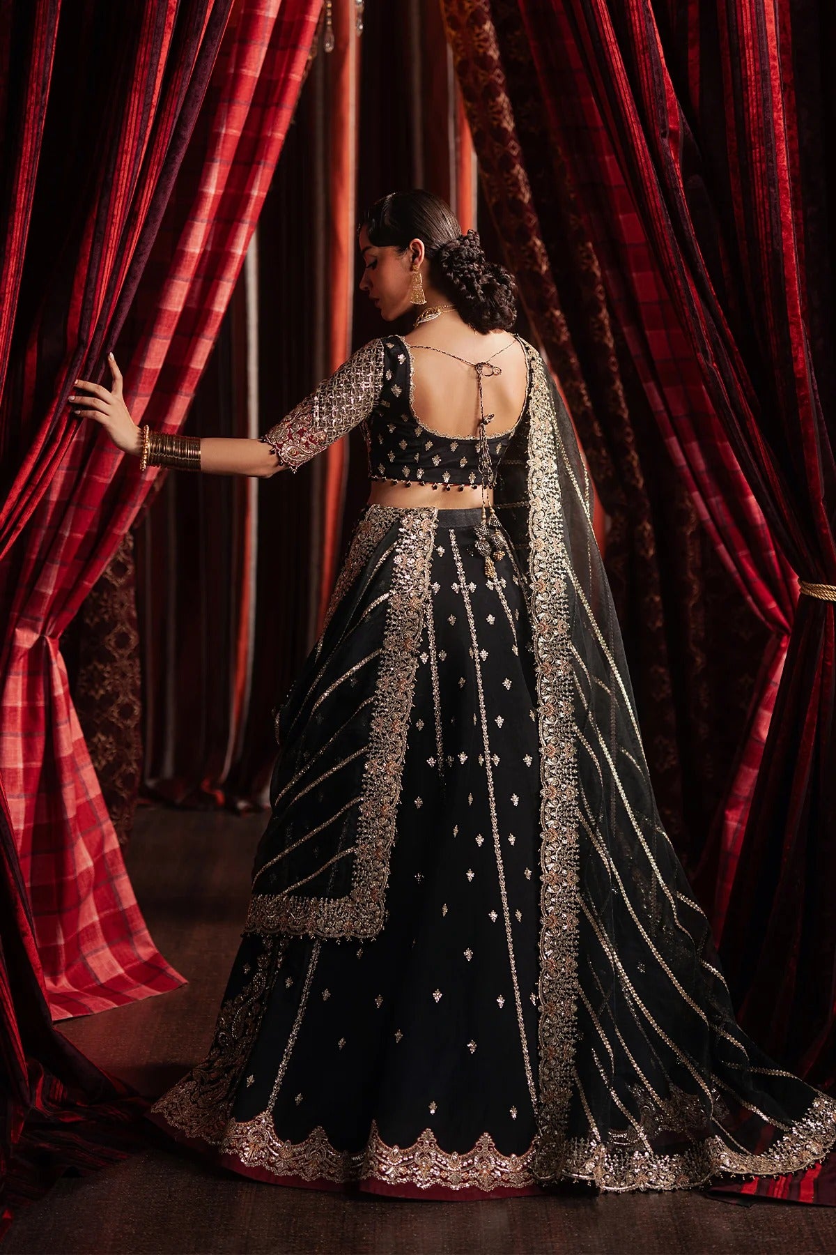Elegant black raw silk embroidered suit featuring detailed front and back panels, organza sleeves, and a richly embroidered organza dupatta with red accents—perfect for luxury festive wear.