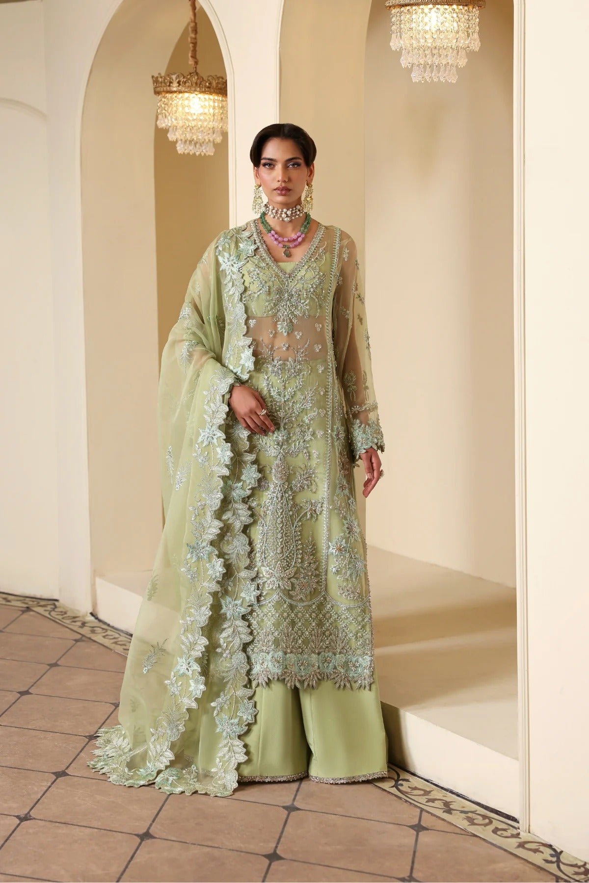 Luxurious organza suit featuring hand-embellished panels, sleeves, borders, and dupatta. Paired with Russian grip inner and 4 yards of raw silk trouser fabric.